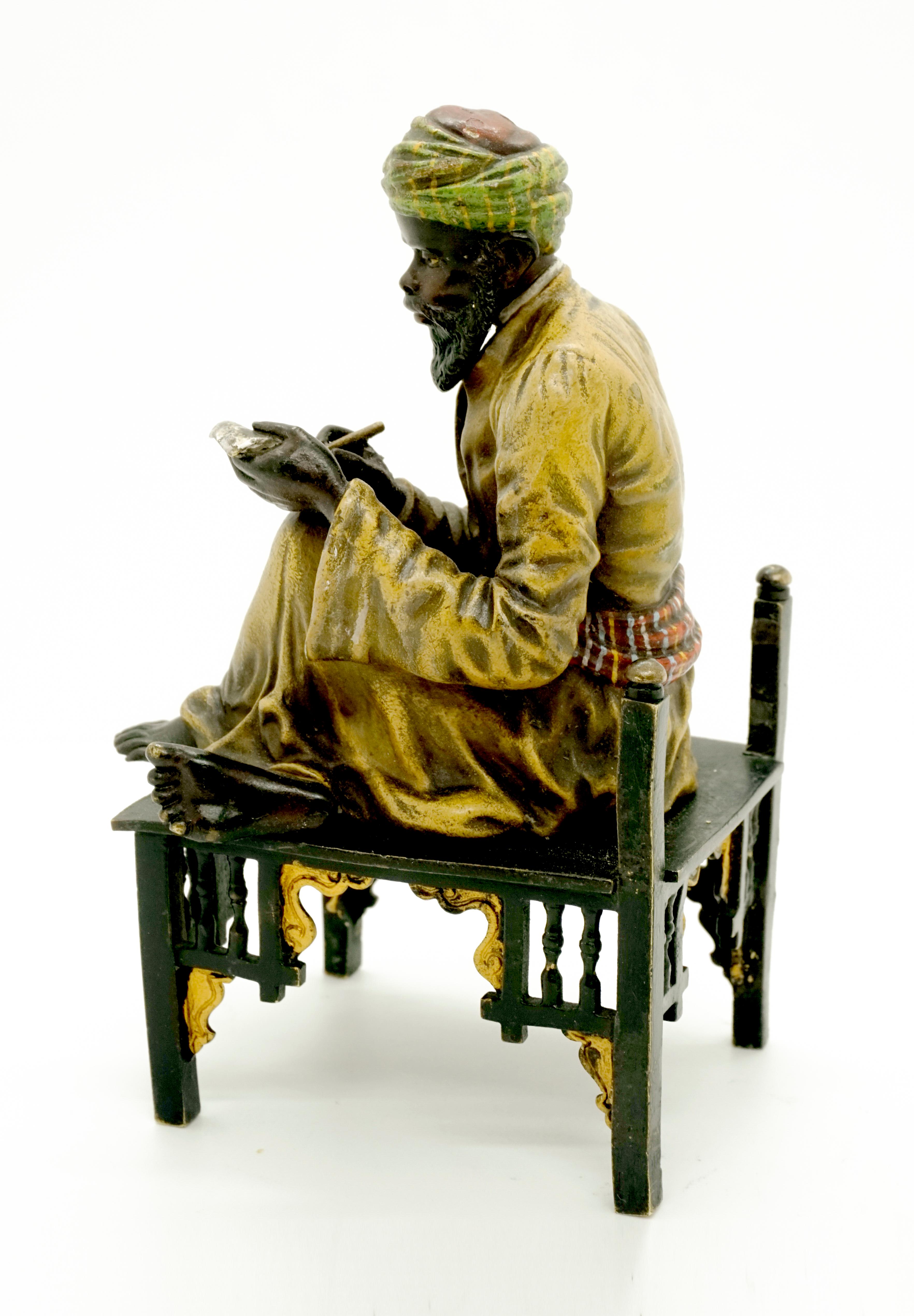 Excellent Piece of Viennese Bronze Art, circa 1900:
A bearded oriental in a long yellow robe and turban sits cross-legged on a wooden bench and writes on a sheet of paper on his left knee. The figure is decorated in color, Bergmann signet on the