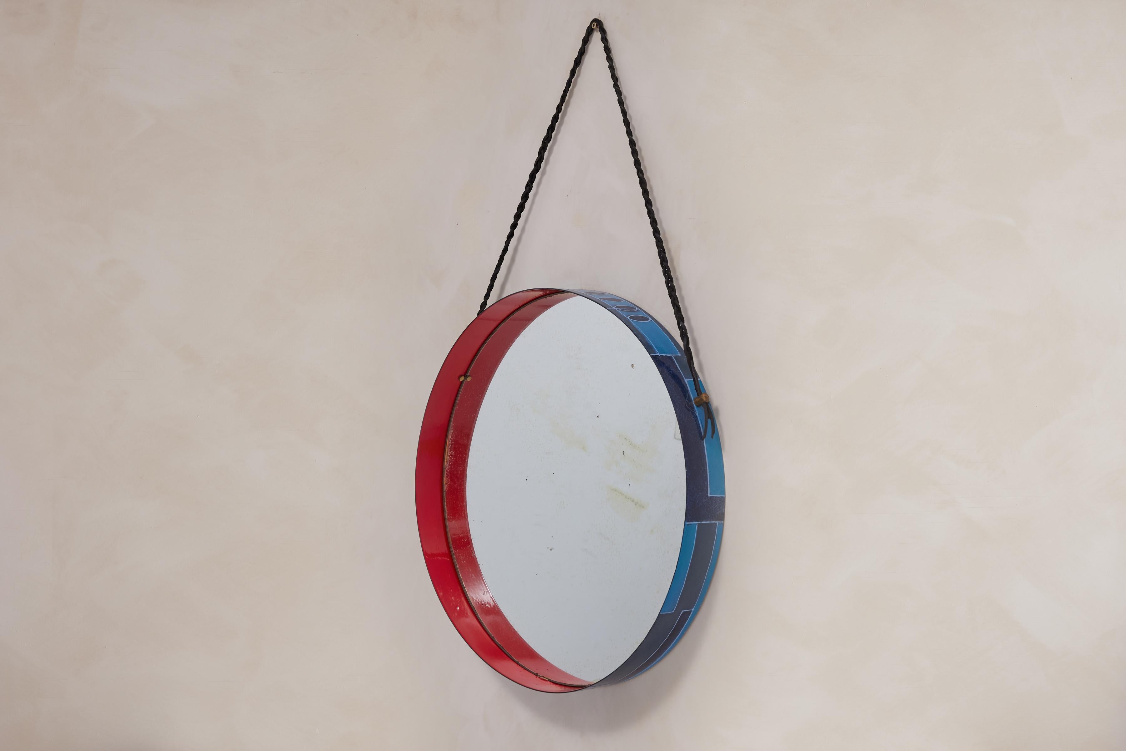 Stunning Italian circular wall mirror with blue and red ceramic on metal frame by Siva Poggibonsi. 

Exterior of frame has painted shades of blue geometric pattern design. 
Interior is painted in a deep red lacquer. 
Original mirror with patina and