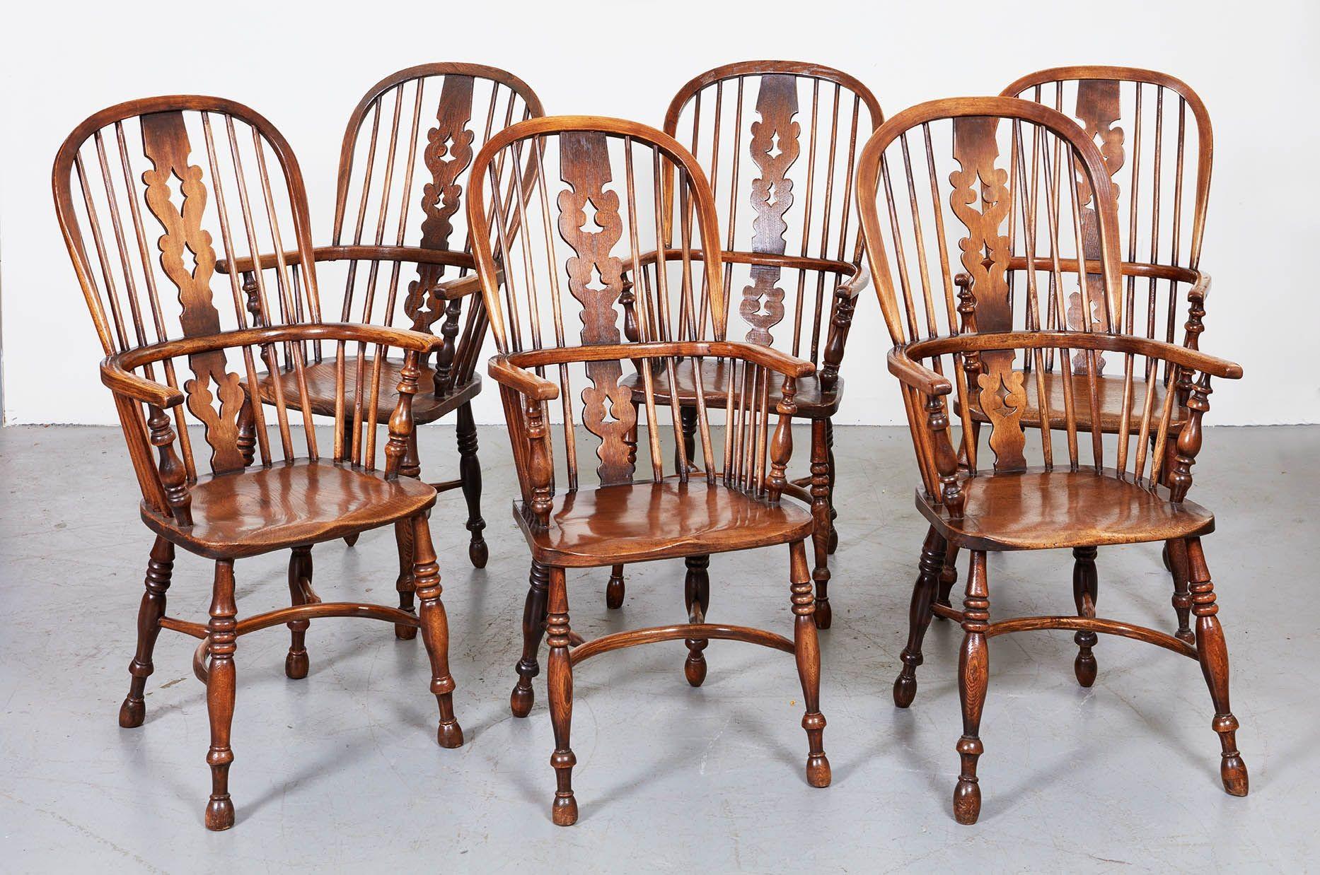 Six windsor armchairs having arched backs and single piece continuous arms, pierced backsplat and spindles socketed into plank seat, and standing on turned legs joined by curved crinoline stretchers. English, mid 19th century. Sturdy and