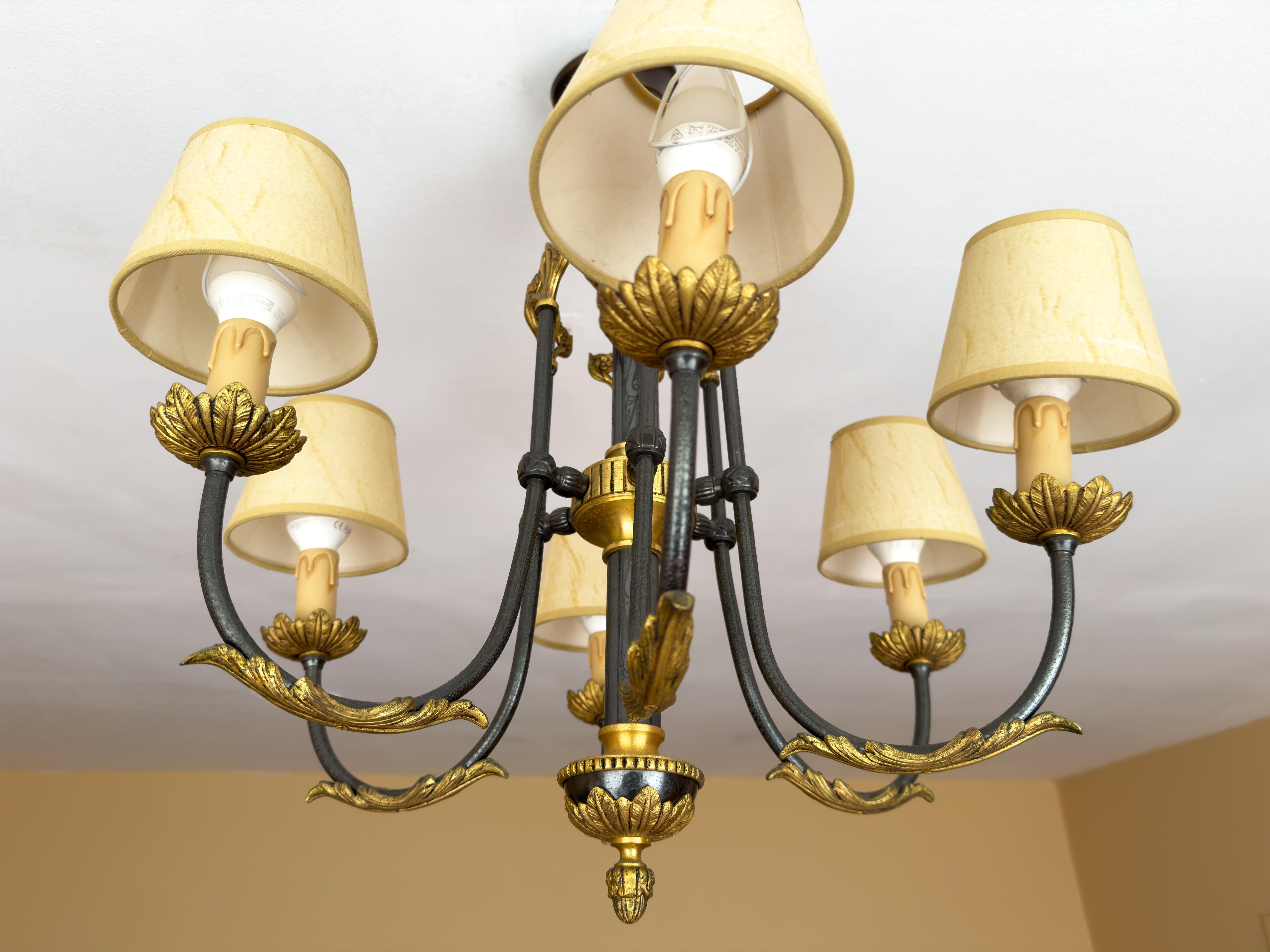 Elegante lampadario portoghese del XX secolo a sei bracci in bronzo dorato e metallo laccato nero.
Questo lampadario riecheggia l'influenza di Luigi XIV con un tocco modernista ispirato alle linee stilizzate dei design della Wiener