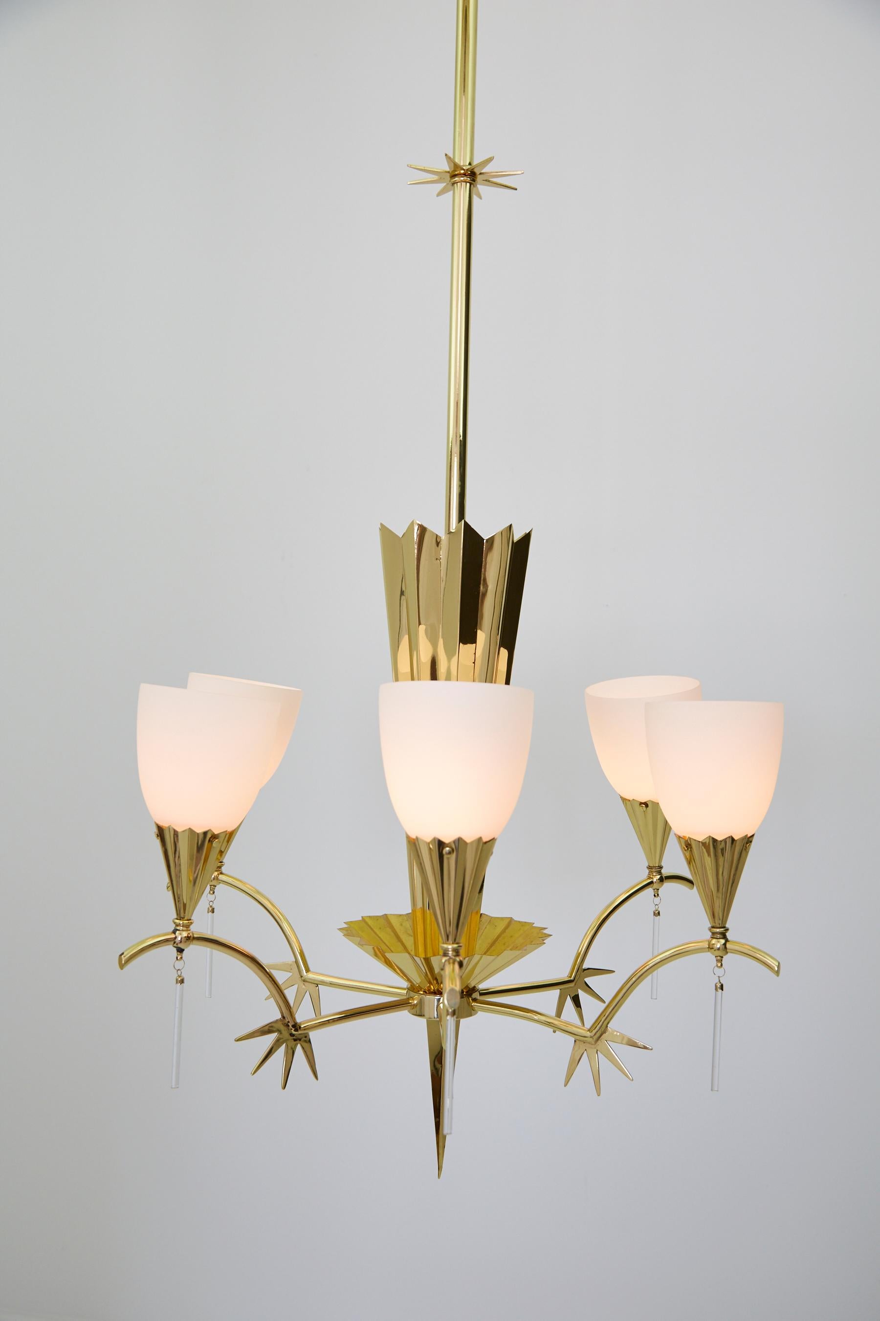 Six-armed Italian brass chandelier with frosted shades and clear glass pendants. Long central brass shaft with trefoil hook at top, extending down to a decorative star shape halfway down. Body of chandelier is comprised of an elongated crown shape