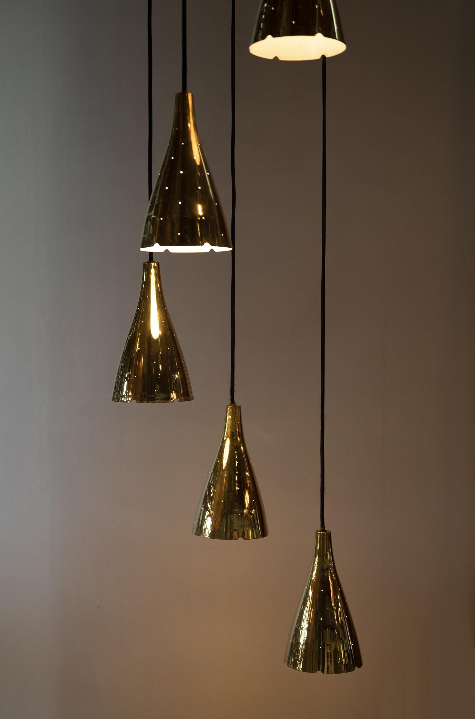 Incredble six adjustable light brass pendant, model 1994/6 designed by Paavo Tynell for Taito Oy, 1950s. Constructed of solid brass with white lacquer interiors, recently professionally polished and rewired.