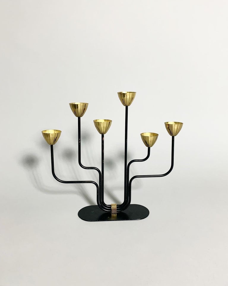 Candelabra designed by Gunnar Ander for Ystad-Metall in Sweden in the 1950s.

Made of solid brass and black steel. Patina to brass and some scratches and chipped off black paint.

Measures: Width: 29 cm
Depth: 6.5 cm
Height: 27 cm.