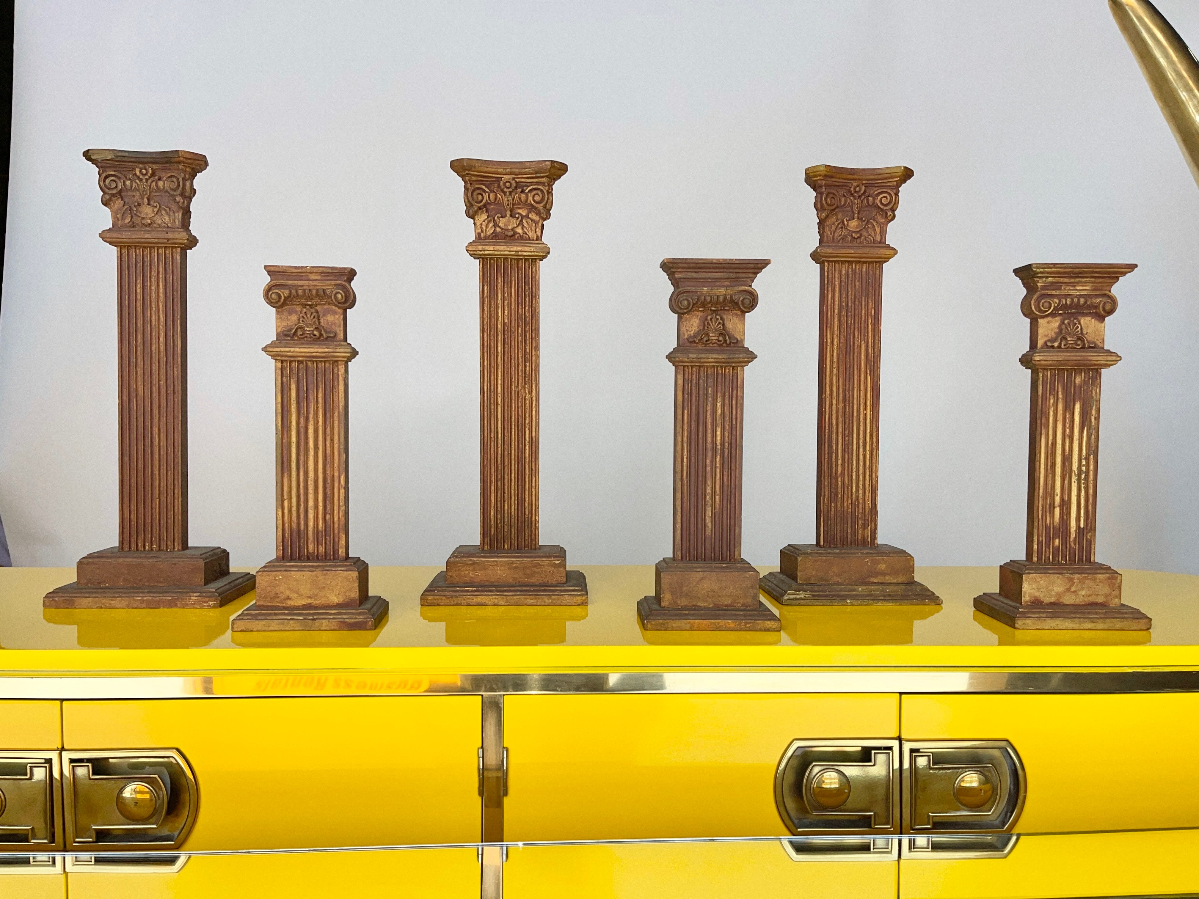 Set of six decorative Ionic and Corinthian columns made of carved wood that has been accentuated with bronze colored leaf.
These were used as merchandising display props at Boston’s legendary jeweler Shreve Crump & Low.

The three taller ones are