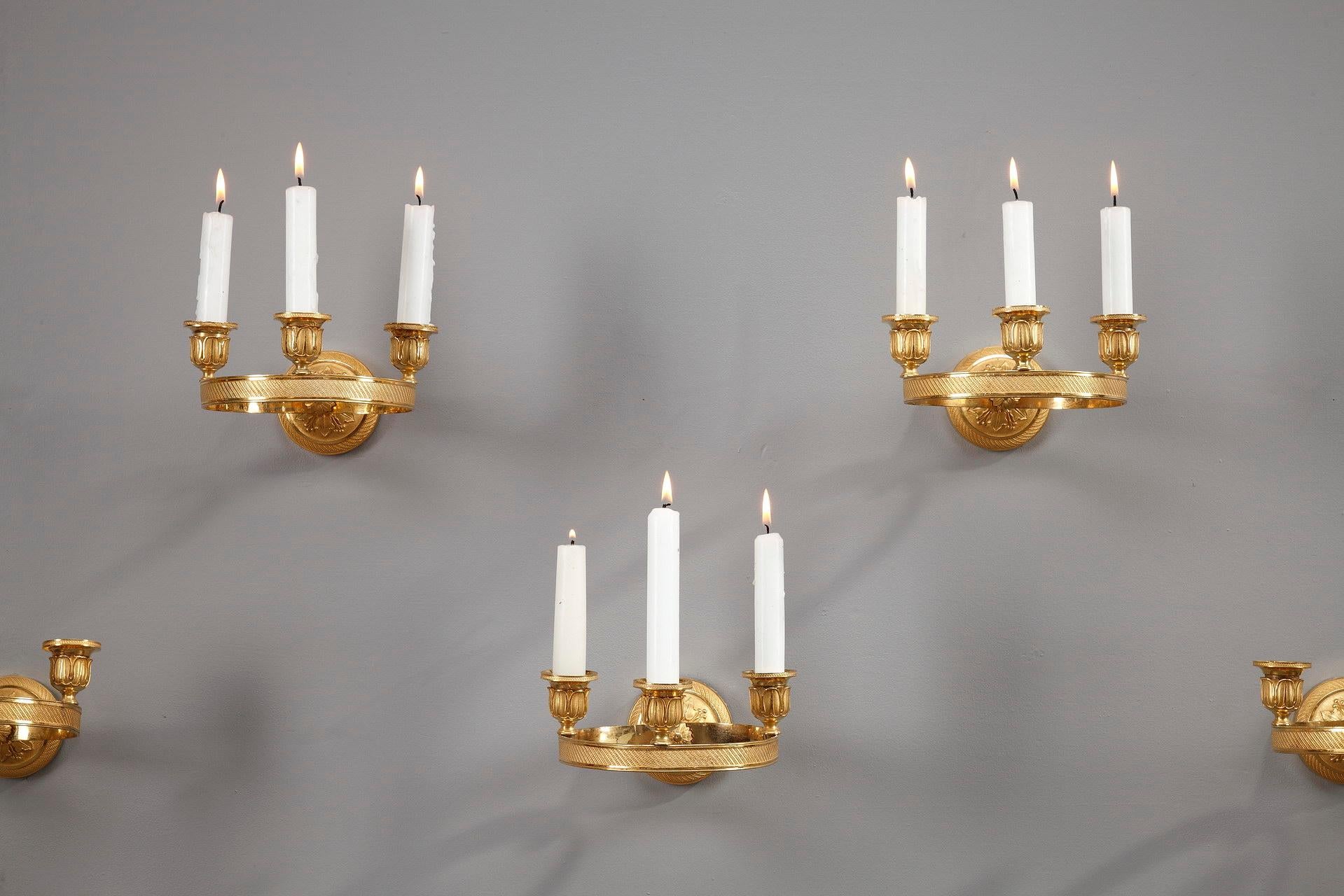 Set of 6 Charles X wall sconces with three lights, circular shape in gilt bronze chiseled with fine motifs. Each sconce, decorated with friezes of fine pearls, is fixed to the wall by a rosette decorated with leaves and fruits. Very beautiful