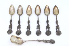 Six cut-silver teaspoons and sugar scoop with floral relief handles