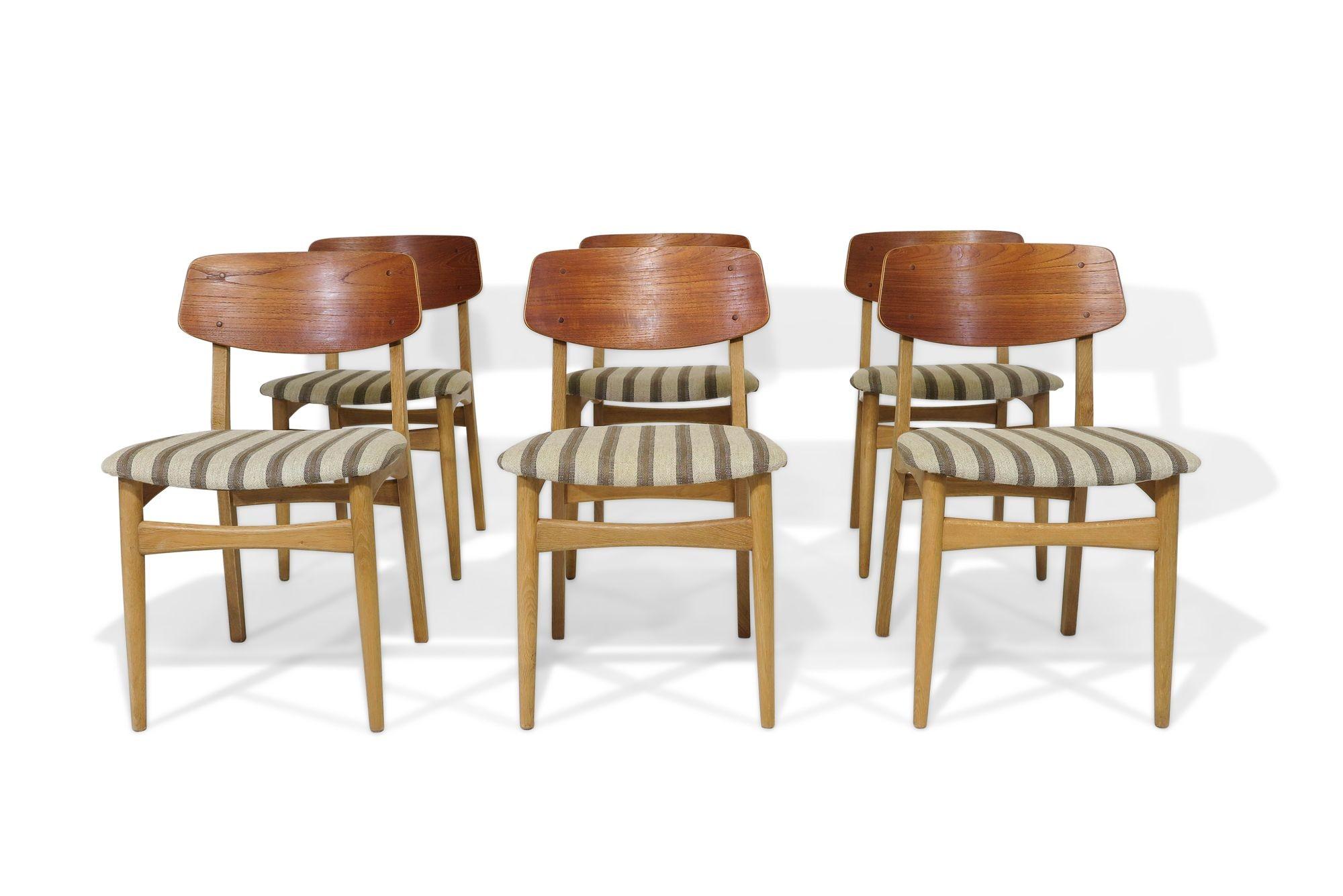 6 Danish dining chairs with teak backs on solid white oak frames. Seats covered in the original wool striped fabric. Wood has been professionally restored. Custom upholstery available upon request. 
Measurements W 18.75'' x D 19.50'' x H