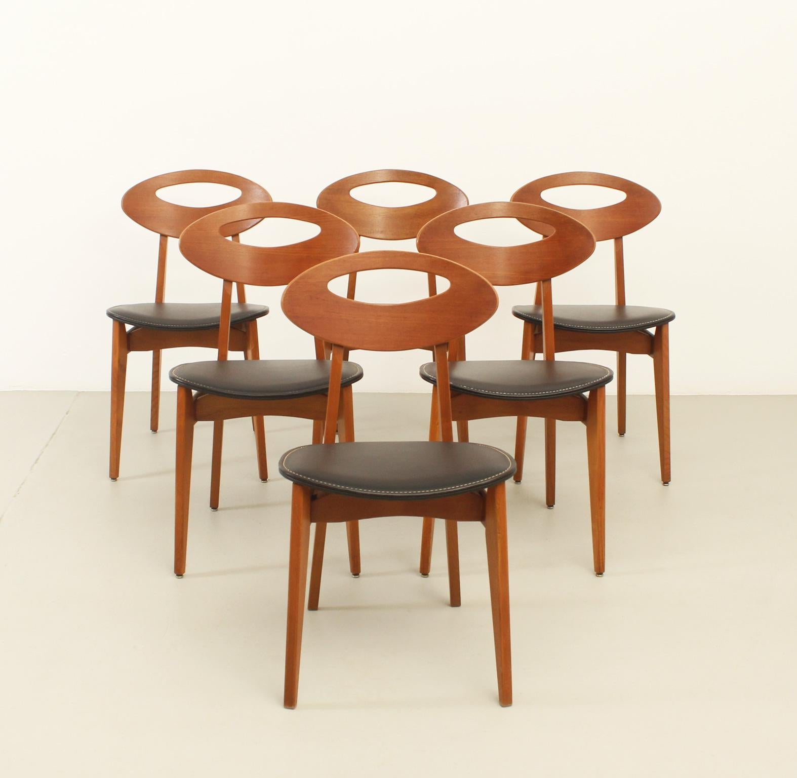 Ensemble de six chaises de salle à manger conçues par Roger Landault pour Maison/One, France, années 1950. Bois de teck et de frêne avec siège en similicuir d'origine avec surpiqûres en fil blanc. 