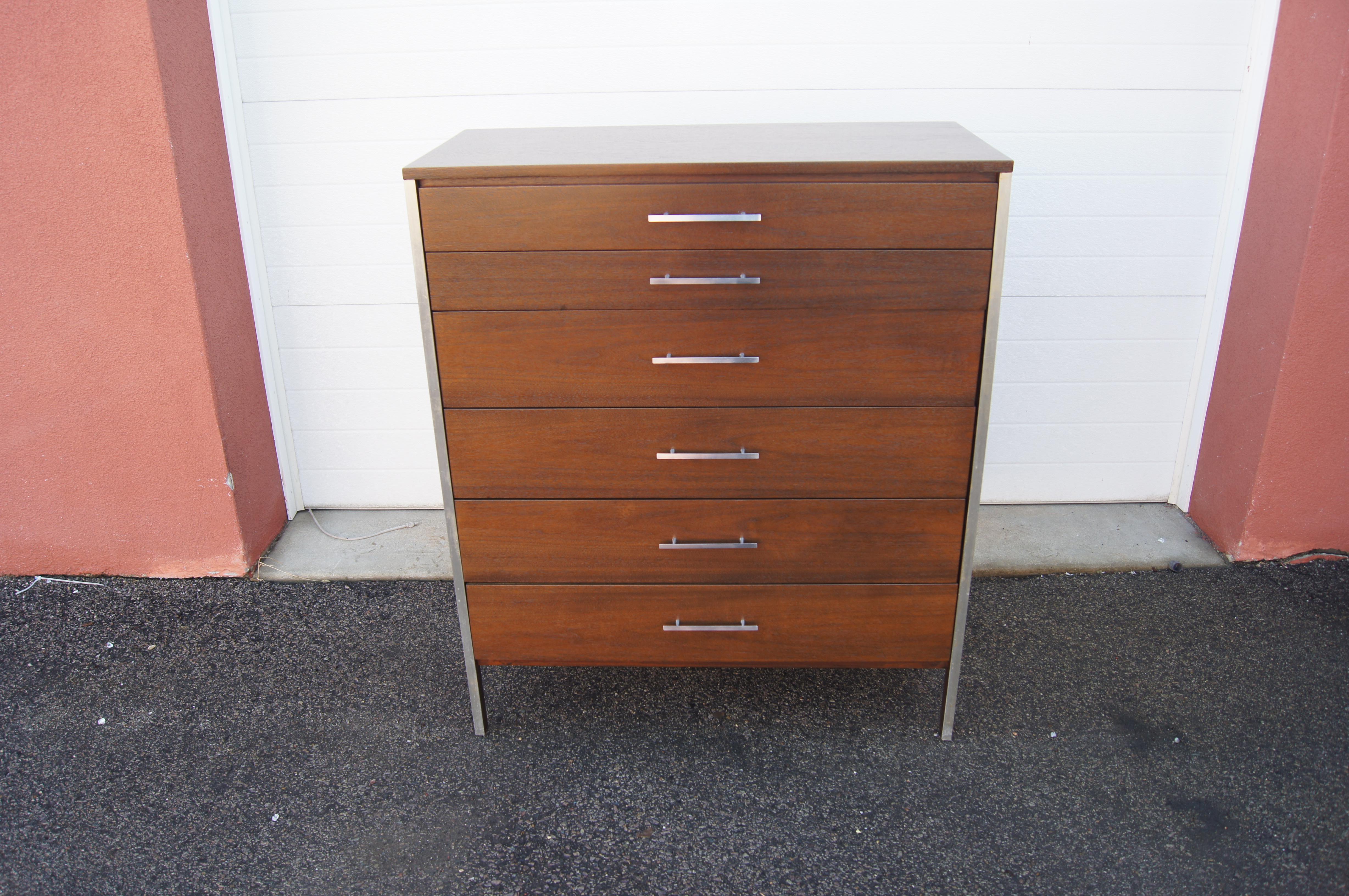 Designed by Paul McCobb and manufactured by Calvin Furniture, this mid-century six-drawer dresser features aluminum accents and slender drawer pulls that emphasize its clean lines and beautiful walnut grain. The topmost drawer is divided into three