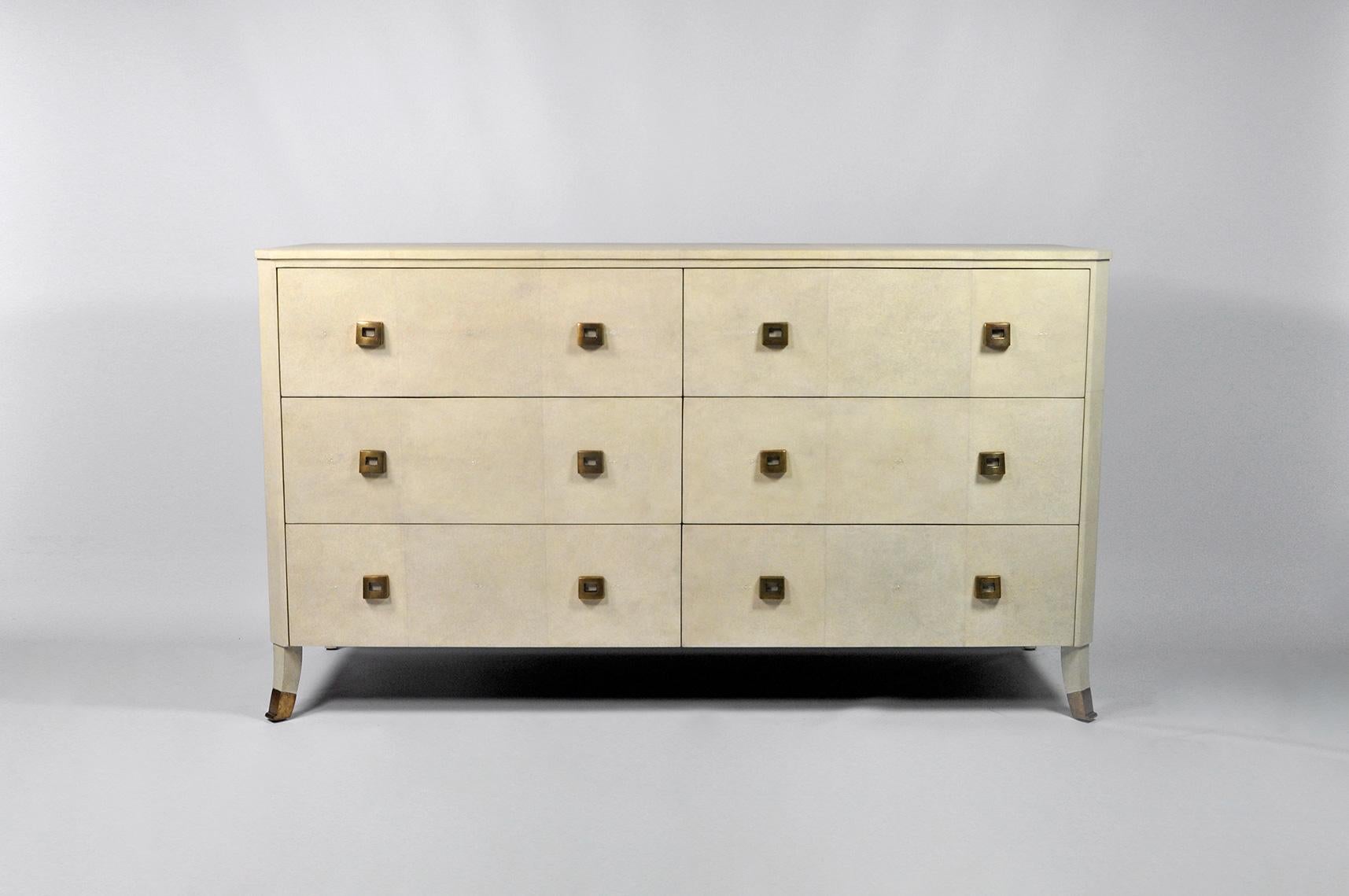 Esta cómoda tiene un estilo art déco clásico. Tiene seis cajones.
Está hecha de piel de raya original en color natural.
Las asas y los pies son de latón patinado envejecido.
El interior de los cajones es de chapa de madera.

Las dimensiones de esta
