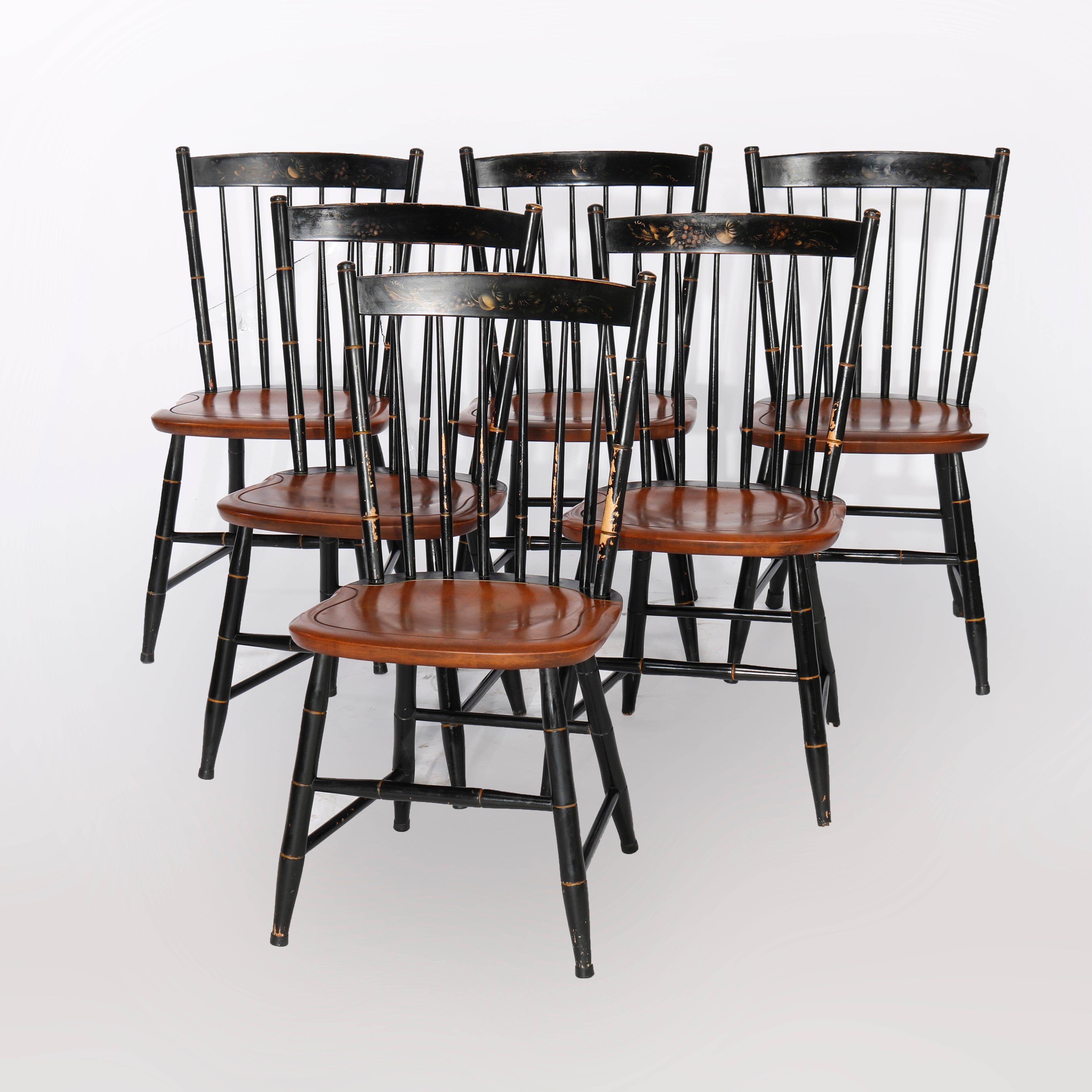 A set of six Windsor style dining chairs offer wood construction with ebonized backs having fruit stenciled rail over spindle supports and raised on flared ebonized legs having gilt accents, 20th century

Measure - 34.25''h x 16.75''w x 17.5''d;