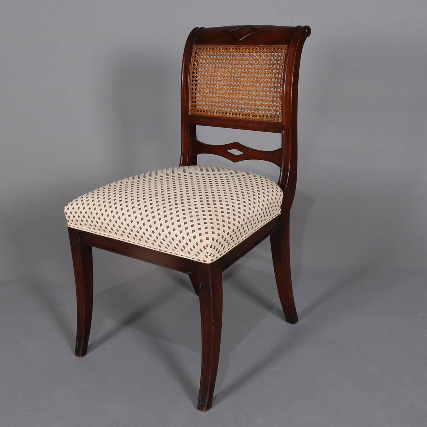 Set of six English Regency dining chairs feature flame mahogany construction with scroll crest having central applied diamond above caned inset and pierced stretcher, upholstered seats raised on flared and tapered legs, 19th century

Measures: 36
