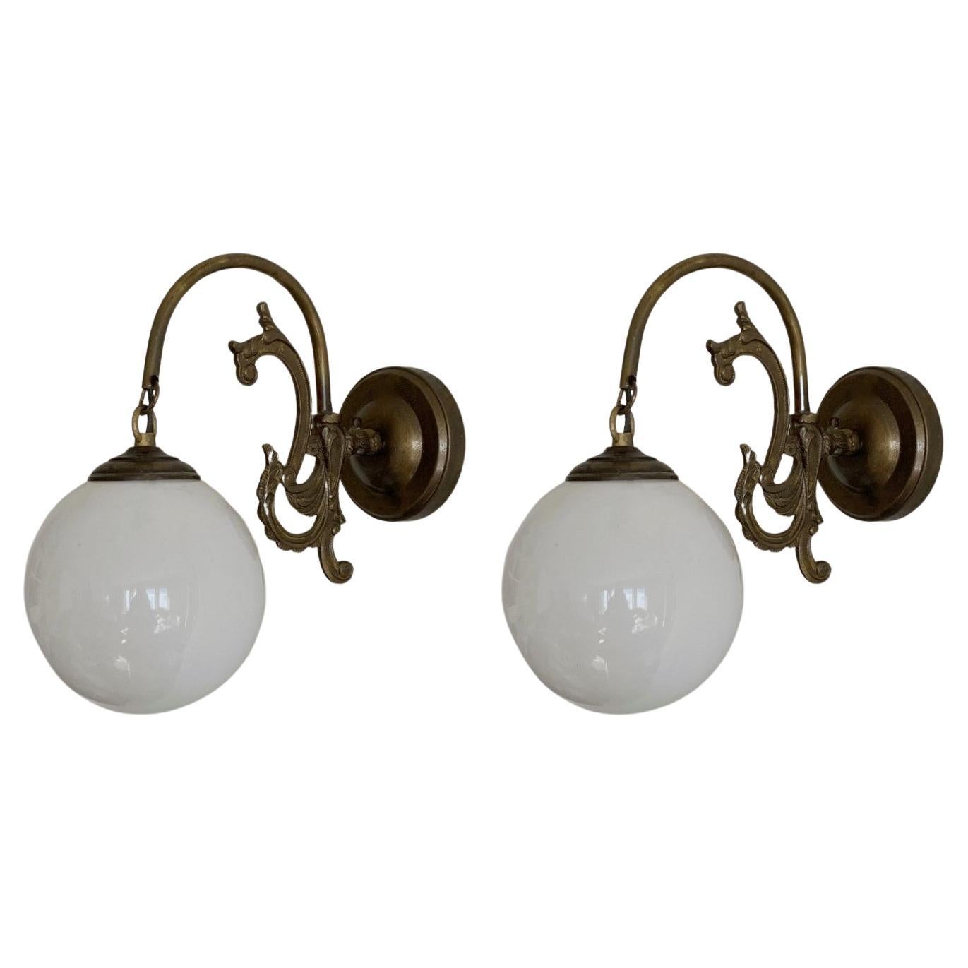 Six bronzed brass wall lights with hand-blown opaline glass globes, for indoor or covered outdoor use, France, 1930-1939. All six wall sconces are in very good condition, beautiful patina, no ships or cracks, rewired. Each sconce takes one Edison