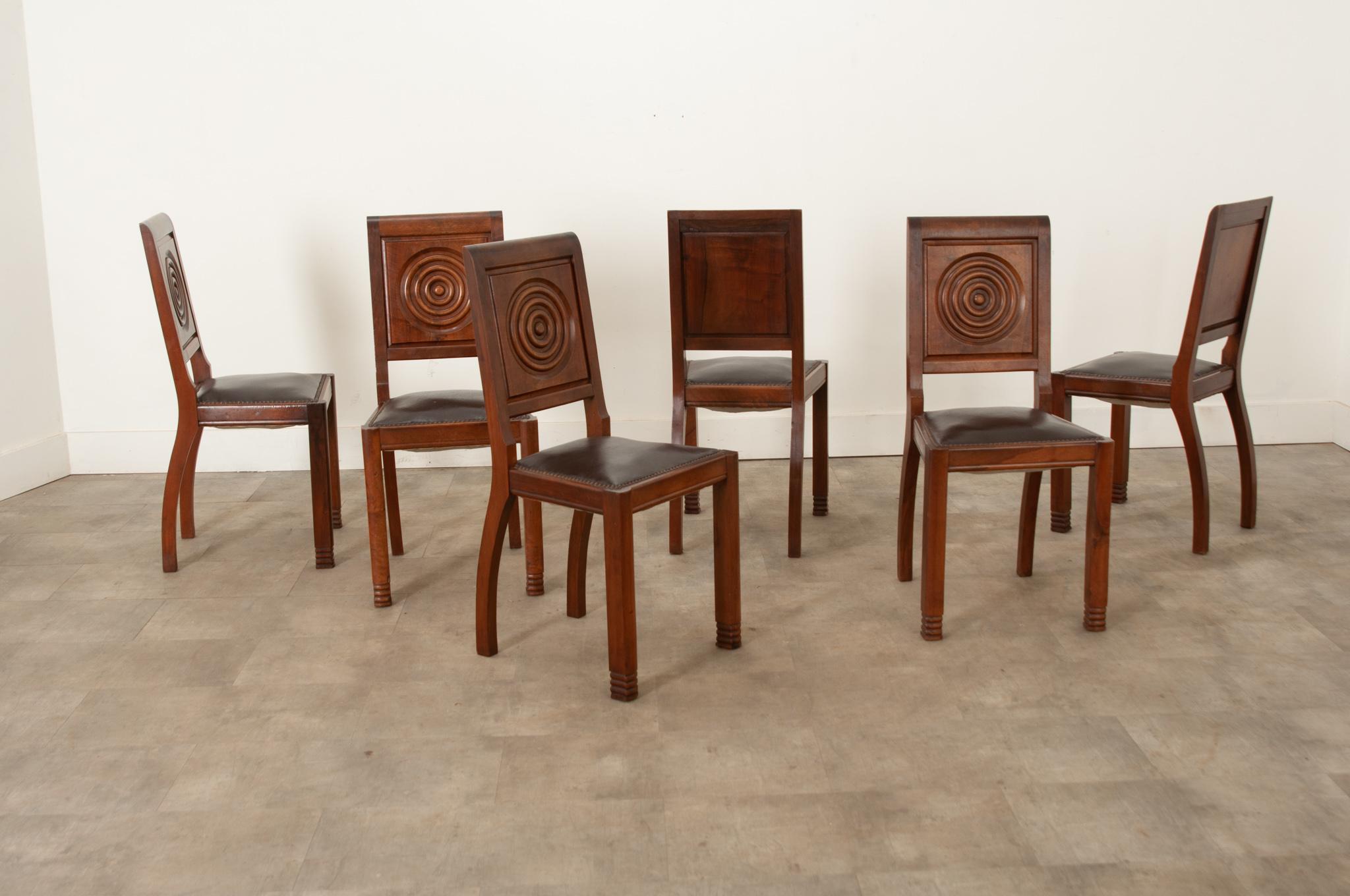 A French set of six impressive Art Deco dining chairs made of solid walnut frames. The detailed and geometric carvings on the backrest panels are very appealing and would meet the standards of the most demanding interiors with elegance and daring.