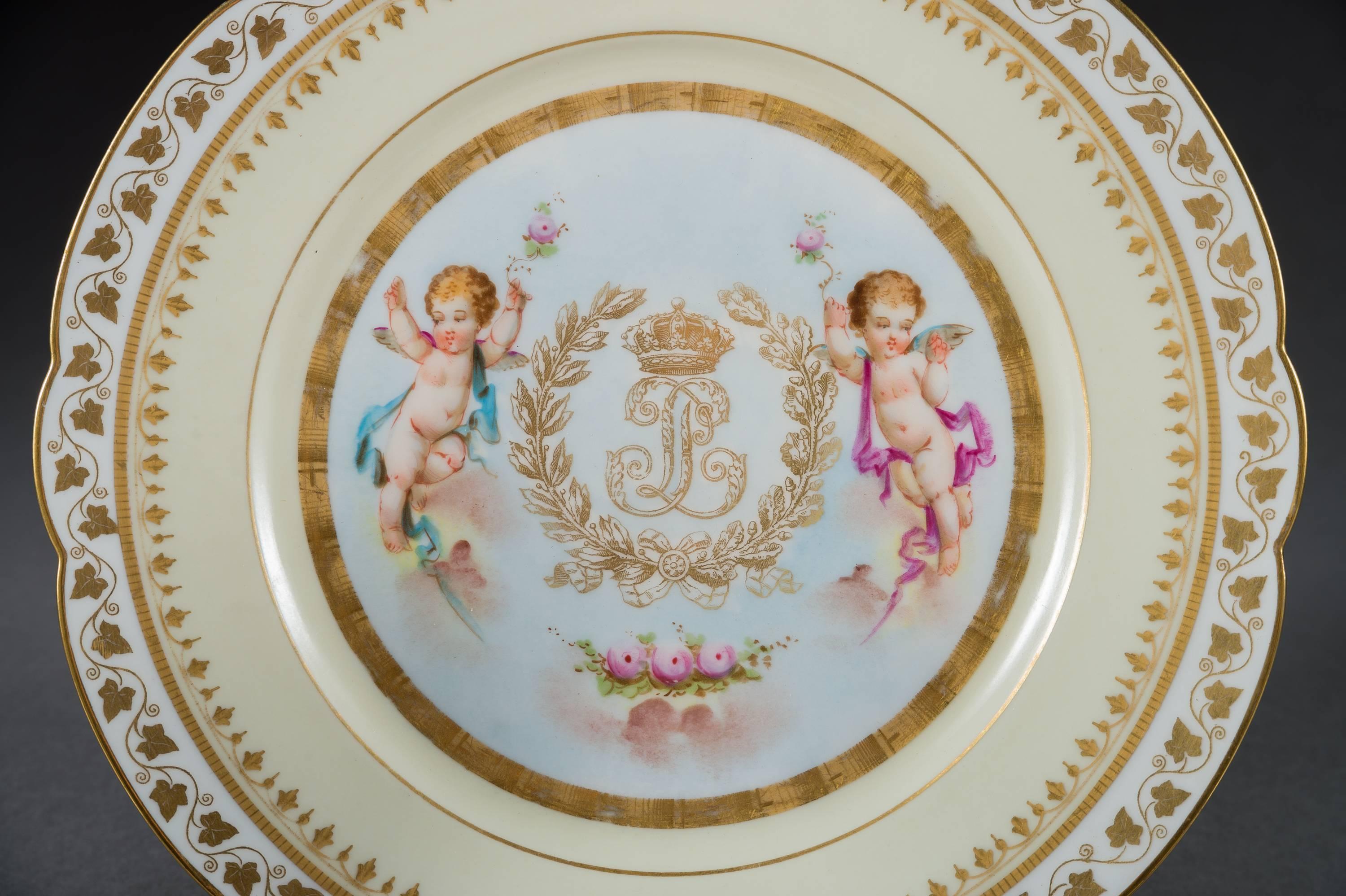 A very fine set of twelve (12) French Sevres pink ground porcelain painted and jeweled plates. 

Each with a gold and pink border with a central painting depicting cherubs with a garland of flowers, with a gold Royal coat of arms. 

Each signed