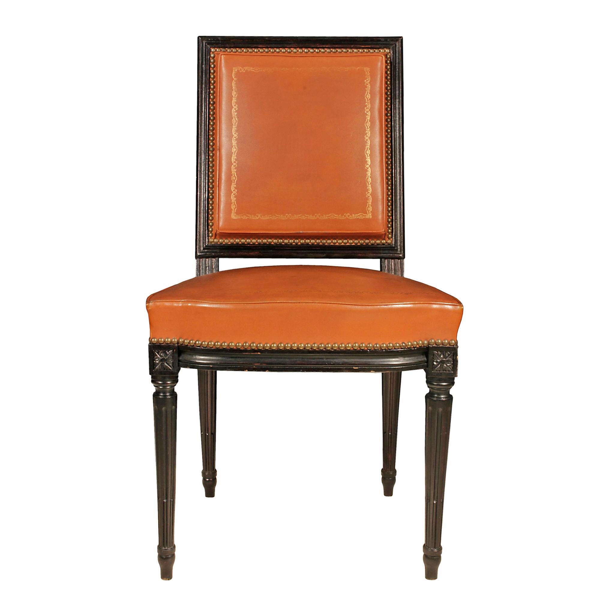 A wonderful set of six French Louis XVI st. turn of the century side chairs. Each ebonized fruitwood chair is raised on tapered reeded legs with rosette block tops. The molded apron continues onto the square back. All upholstered with a cognac gilt