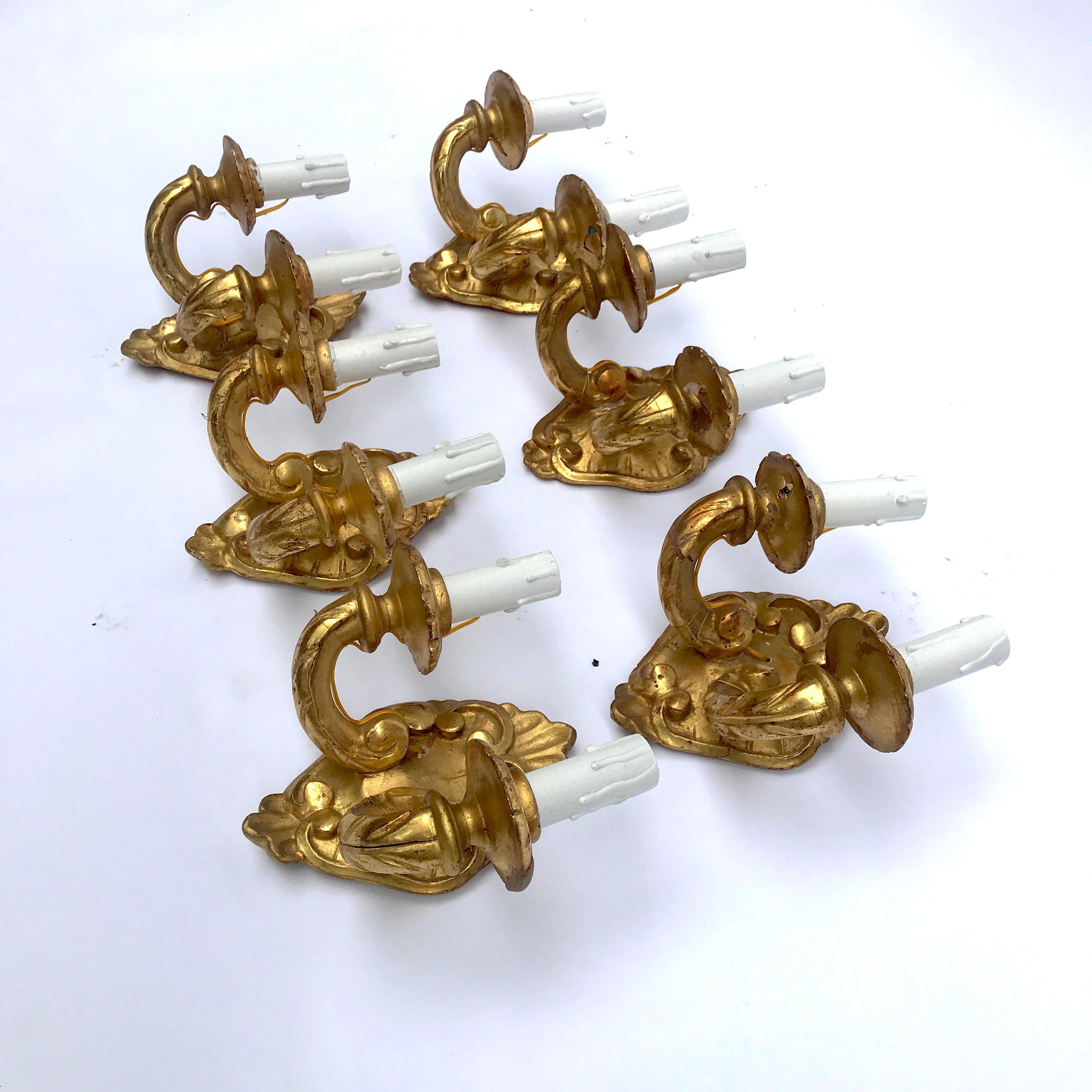 A set of six antique Italian giltwood sconces from Tuscany, shaped two-light sconces, realized in linden wood, carved with vegetal patterns, beautiful gilding, dating back to late 19th century. It is unusual finding a set of six antique Italian