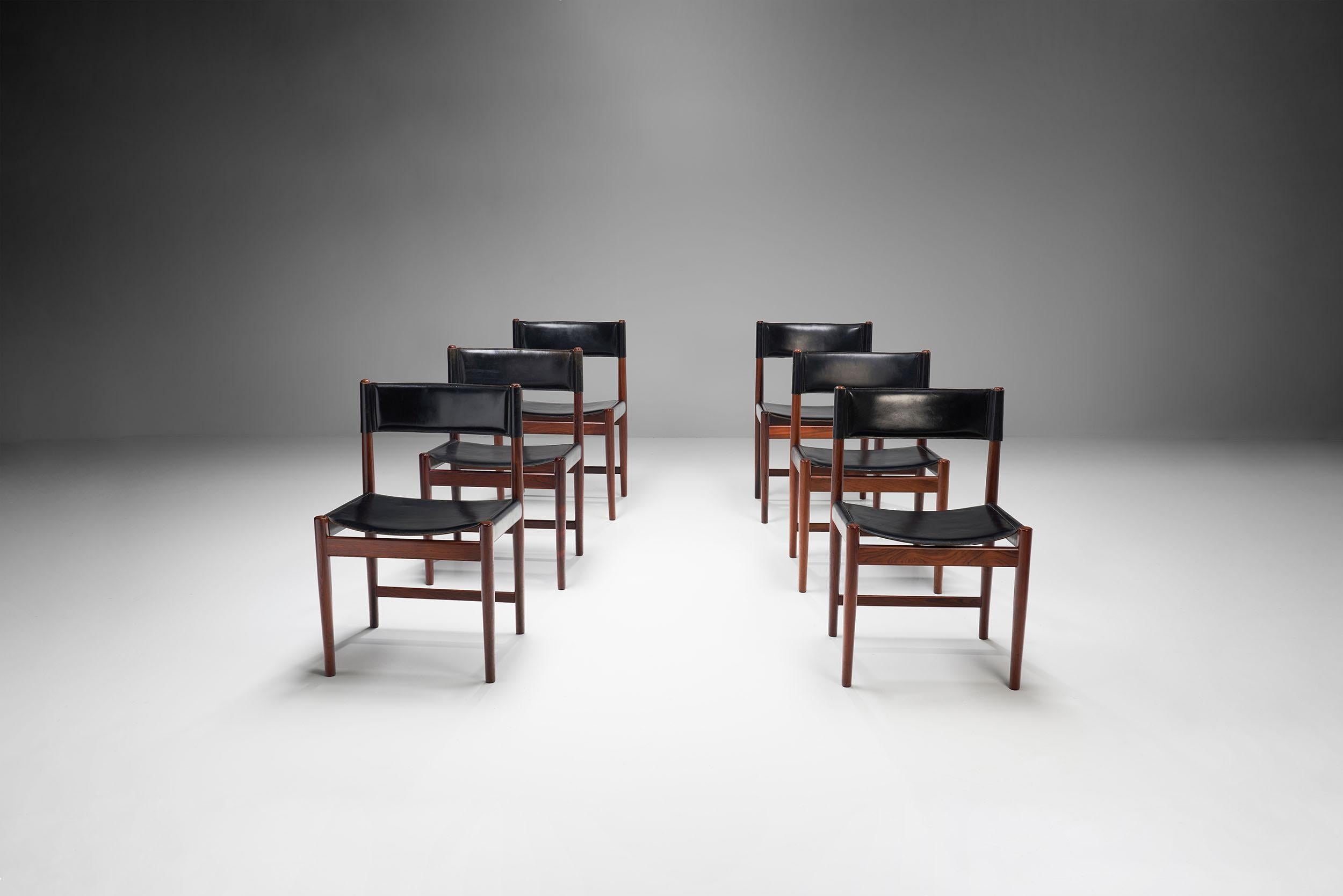 Dieses Set aus sechs Esszimmerstühlen des dänischen Designers Kurt Østervig ist ein schönes Beispiel für schlichtes, raffiniertes dänisches Design aus der Mitte des letzten Jahrhunderts.

Die schwarzen Lederstühle sind aus massivem dunklem Holz