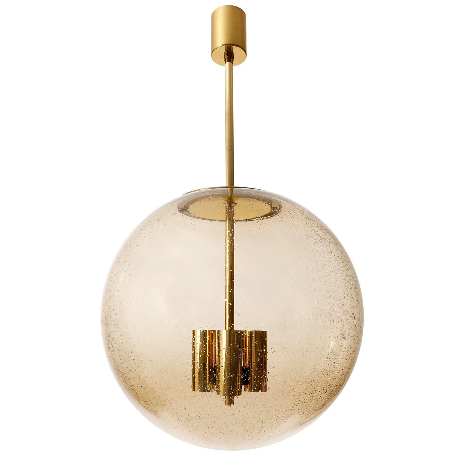One of six extra large brass and hand blown glass globe pendants model 'P 197' by Glashütte Limburg, Germany, manufactured in midcentury, circa 1970.
The suspension, rod and canopy are made of polished brass. The seeded glass globe with many air