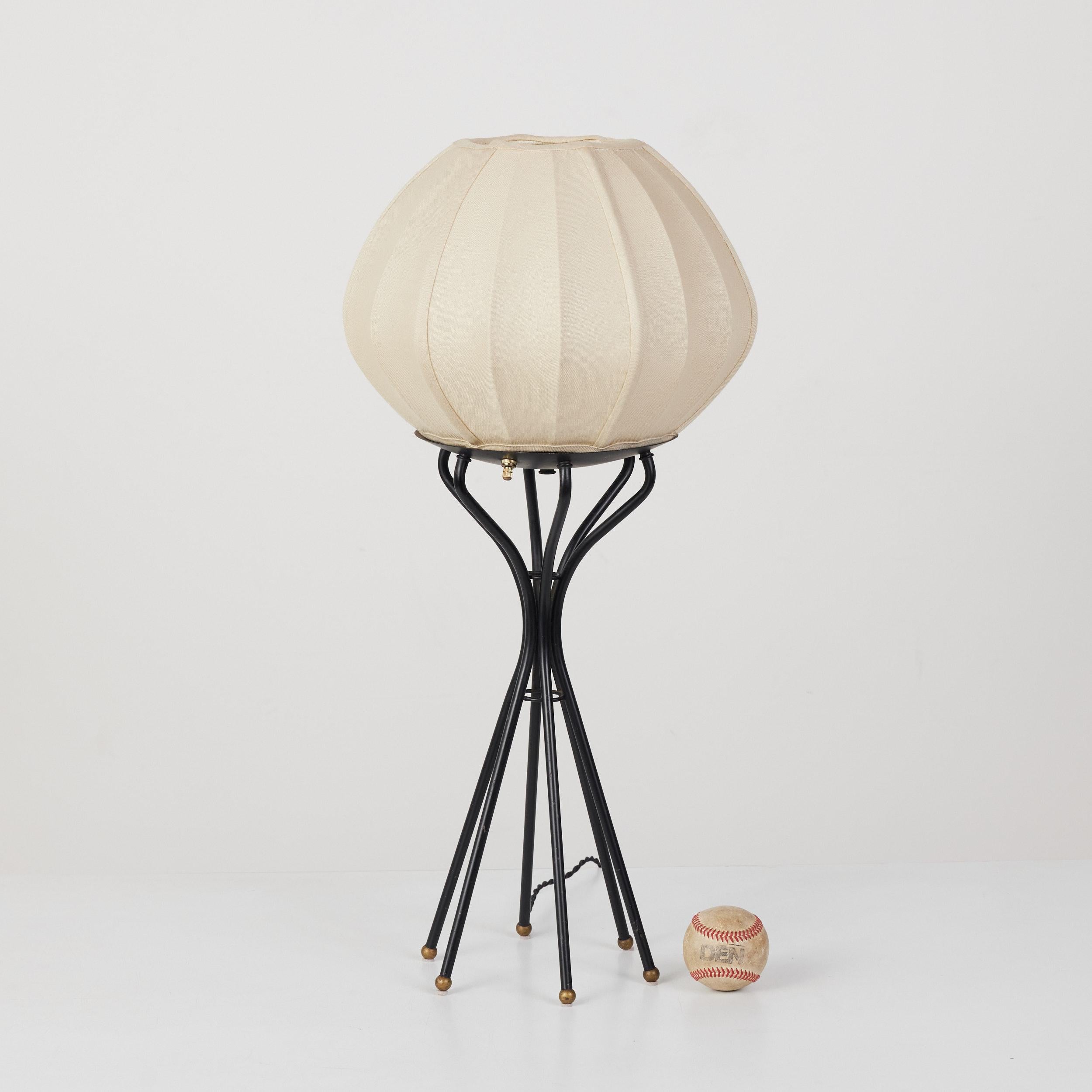 Table lamp features a linen wrapped shade on an enameled steel frame. The base of the lamp splays out to six legs, each finished with a brass ball foot. The lamp has a brass on/off switch on the bottom of the shade. This piece has been newly rewired