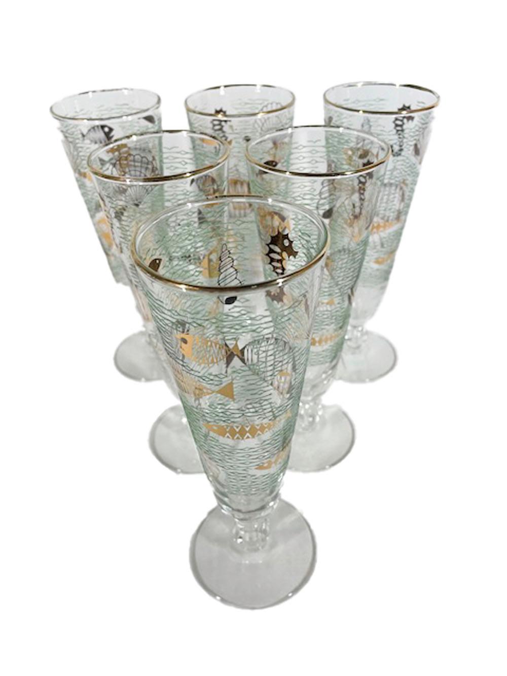 Six footed pilsner glasses with a lobed ball stem decorated with 22k gold Atomic style fish and other marine life against a ground of waves in raised translucent green enamel. Made by Libbey glass and called 'Marine Life' this pattern was