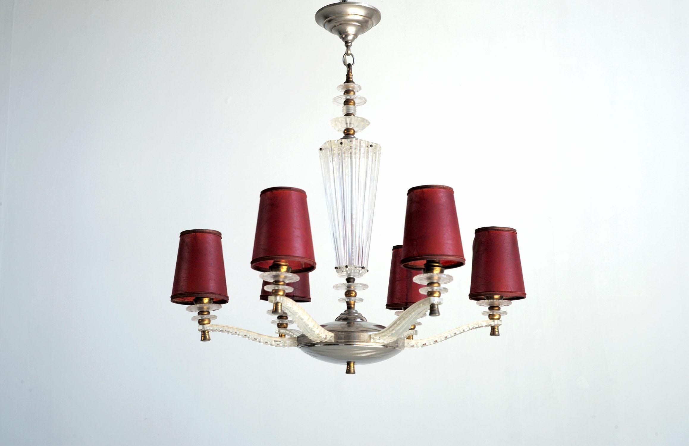 Chandelier with 6 sconces, France 1950. Enhanced with gilded and chromed brass parts, this methyl methacrylate luminaire insolently imitates the neo-classical chandeliers of the 1930s. The clip-on lampshades are in blushed parchment. 
