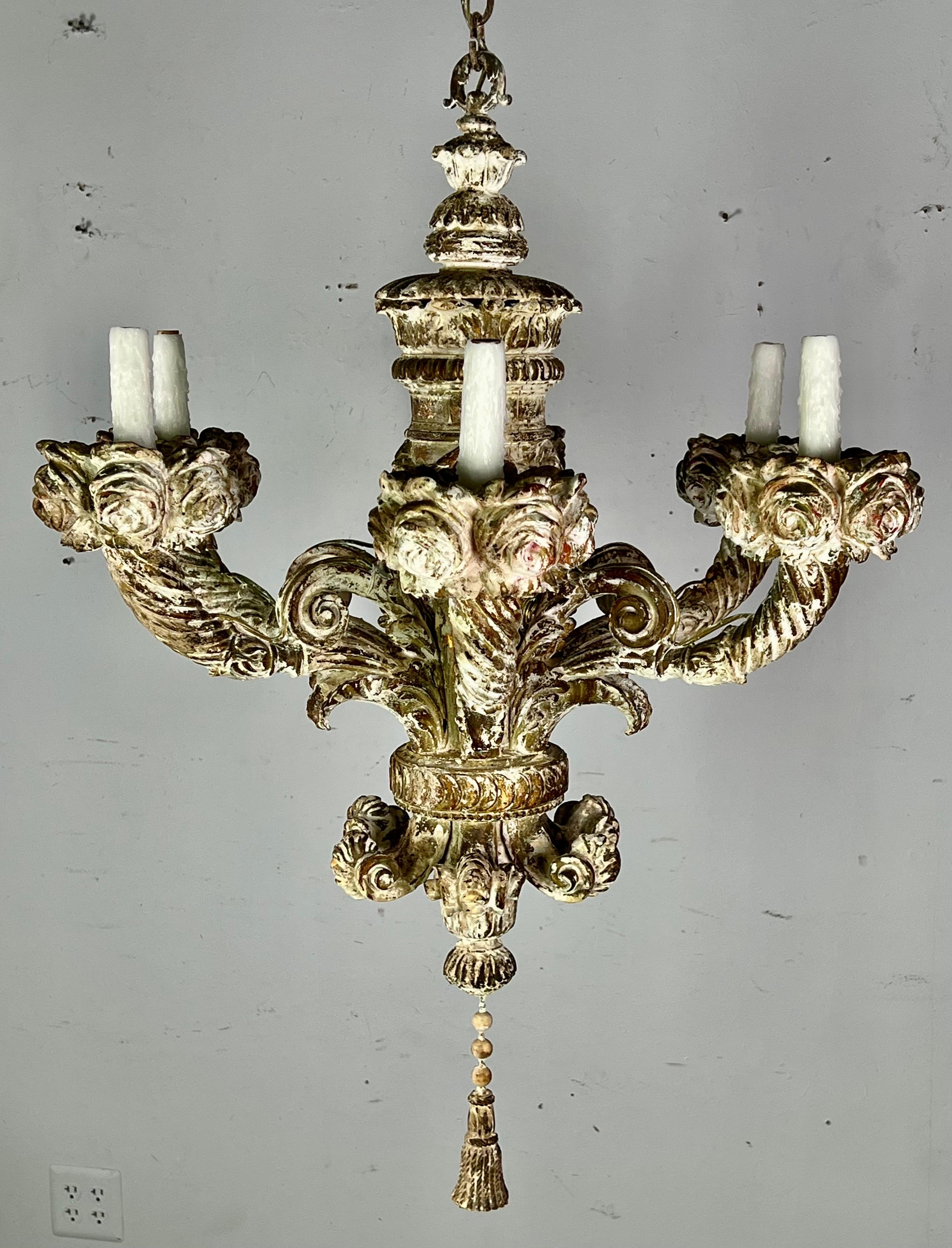 Six light 19th century carved wood French chandelier with beautiful worn painted finish throughout. The fixture is newly rewired and includes chain and canopy. Carved roses, acanthus leaves, scrolls and a carved tassel can be seen as well.