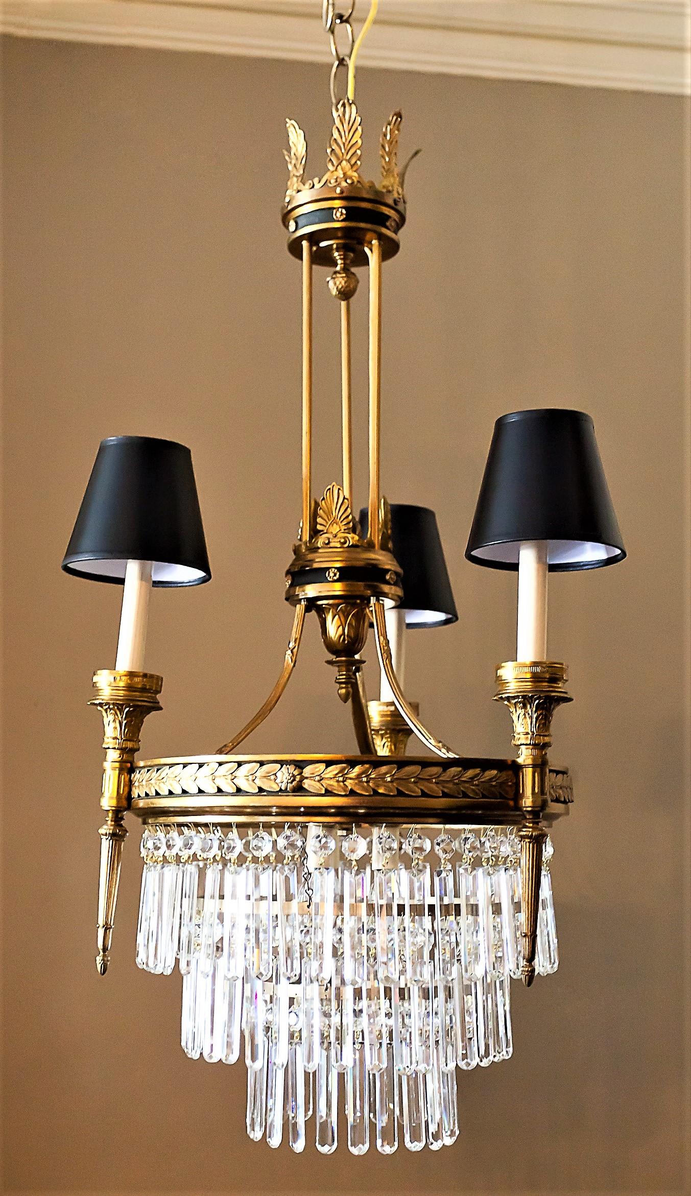 This Belle Époque/Edwardian chandelier has three external torchere-style lights with shades and three internal lights. Hand-cast gilt and patinated brass. Laurel leaf garland band. Three black parchment shades, hanging hardware, ceiling cap, and one
