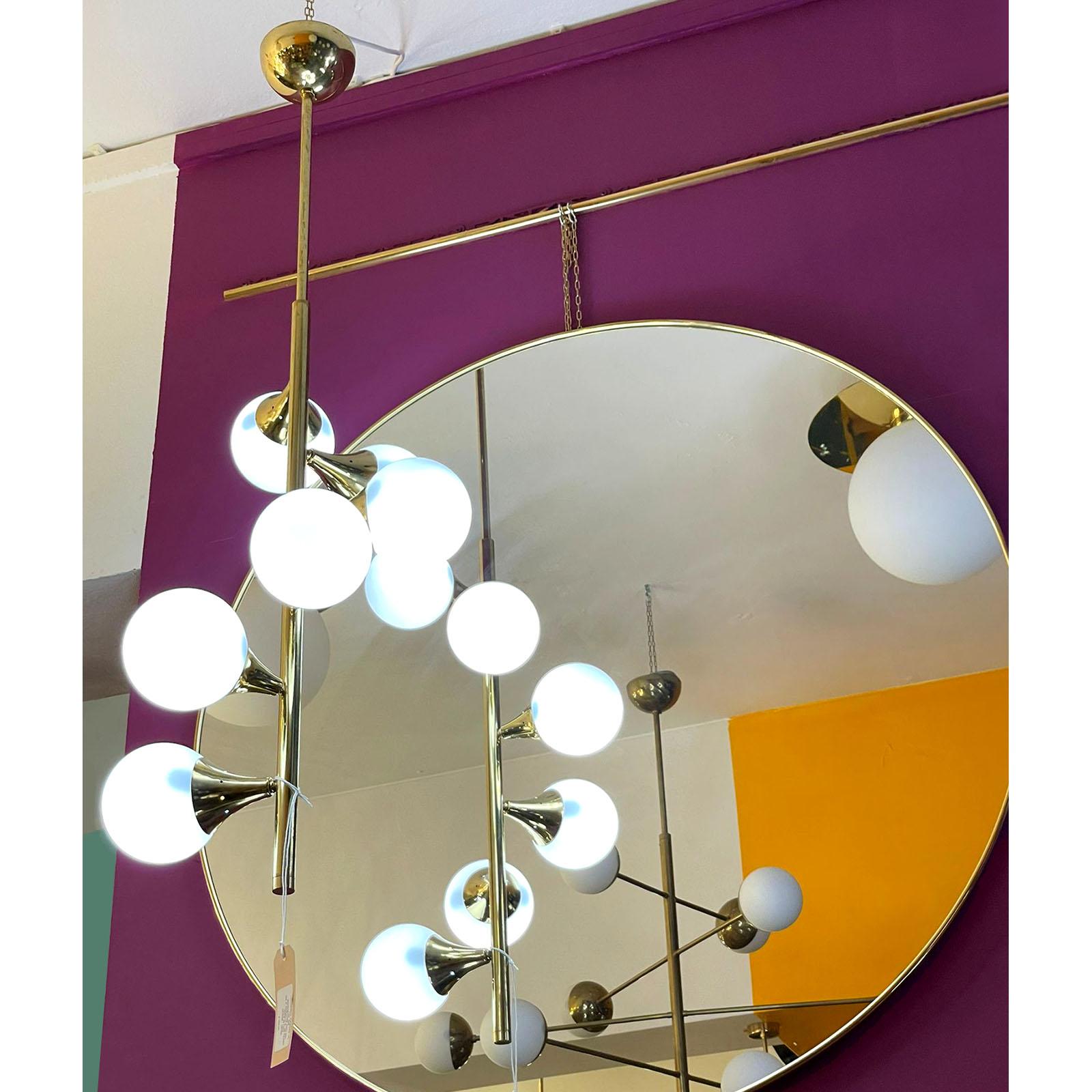 Six light mid century Stilnovo style chandelier featuring a brass pole shaped body onto which are attached, in a swirling pattern, brass light sources which hold white glass globe light diffusing shades.

Dimensions: Diameter 34 cm; Height 115 cm;