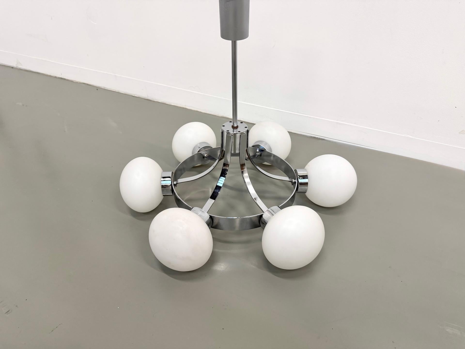 Lampe suspendue à six lumières inspirée par Gaetano Scolari pour Guzzini, Italie, vers 1970. Structure circulaire en métal chromé équipée de six globes en verre opalin blanc. Un design géométrique et équilibré, typique de la période italienne de
