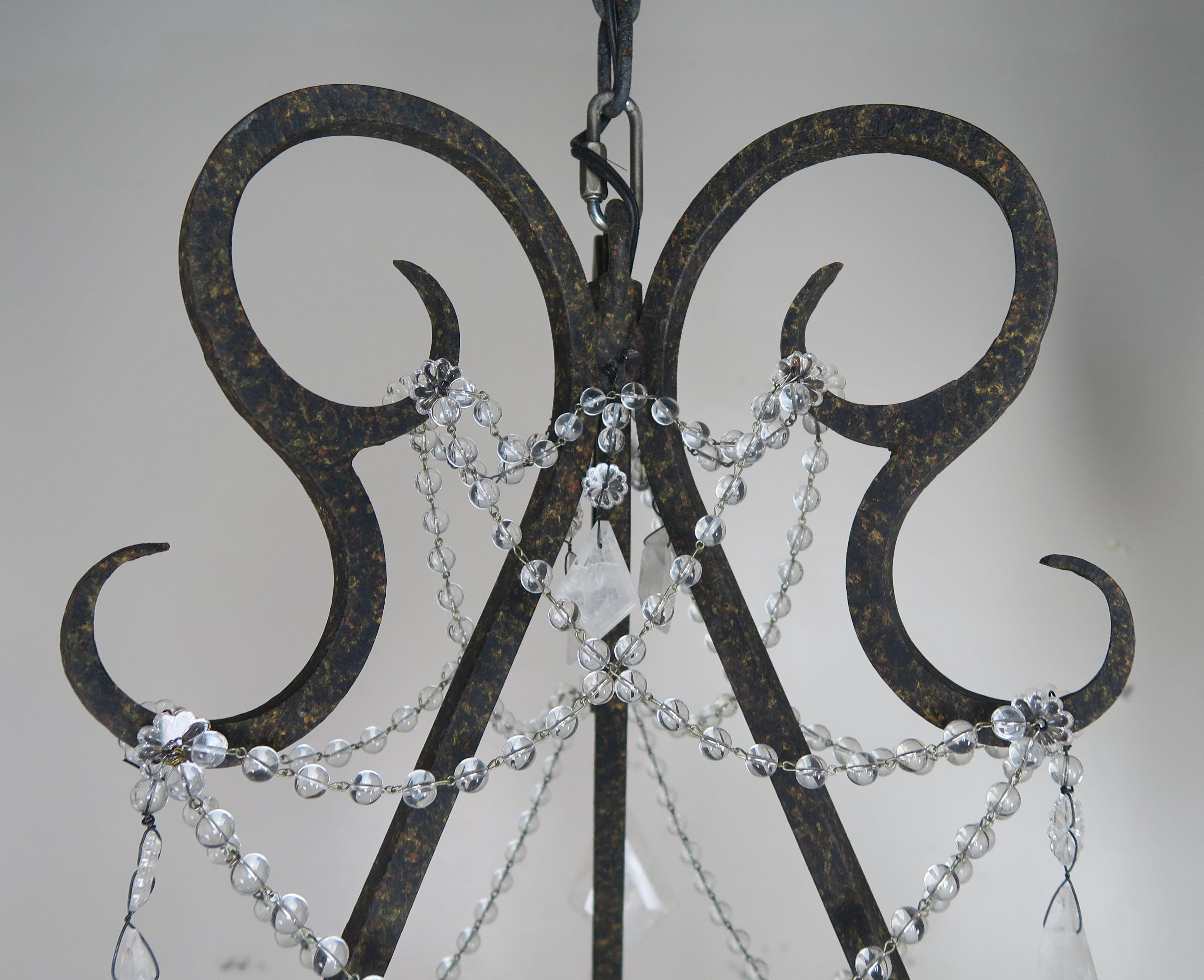 20th century handwrought iron six light chandelier adorned with rock crystal pendulum shaped drops and garlands of crystal beads throughout. Center crystal finial. This fixture is newly rewired with drip wax candle covers and includes chain and