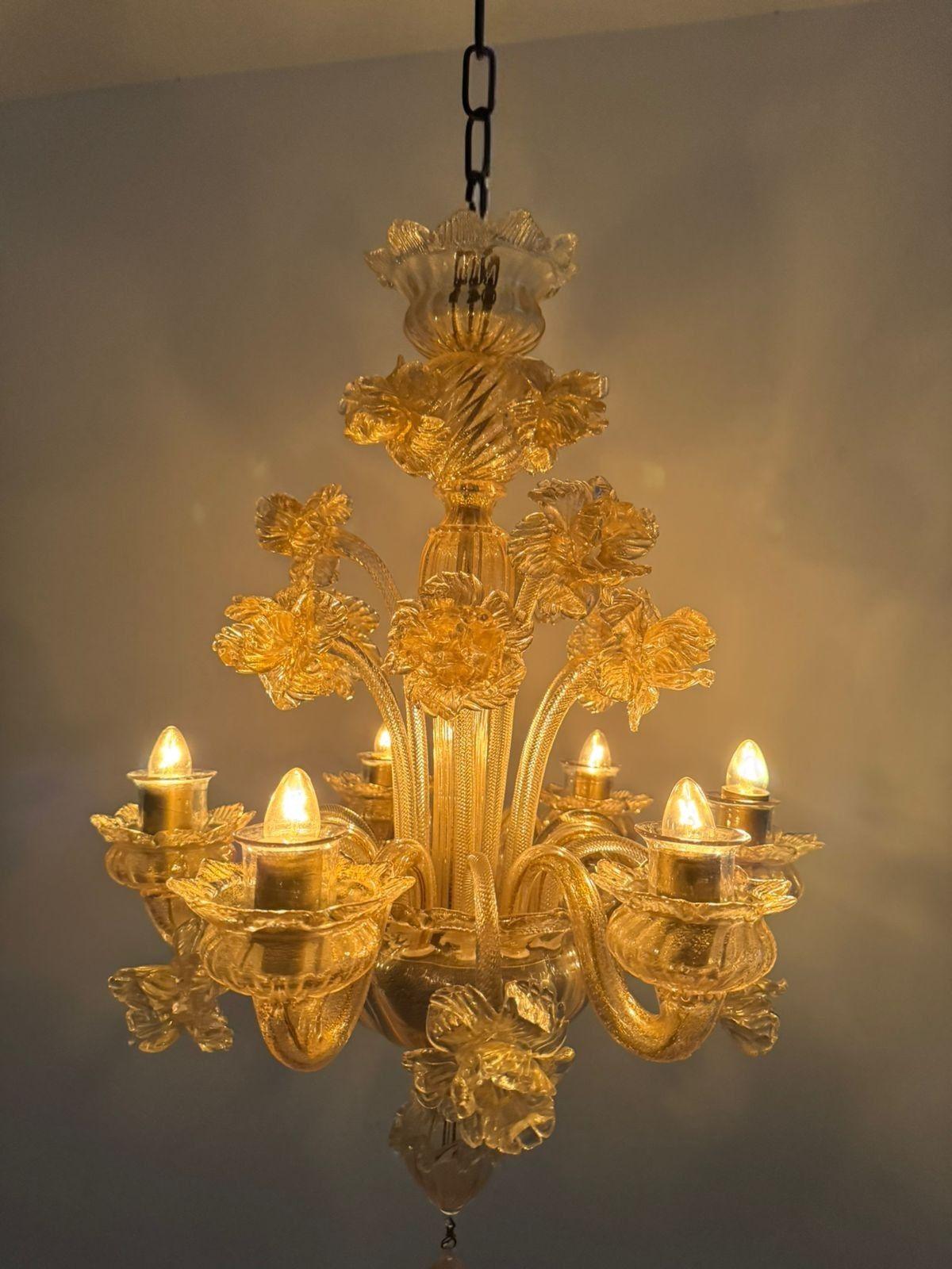 Bellissimo lampadario a 6 luci in vetro di Murano, prodotto intorno al 1950 e attribuito a Seguso, con dettagli floreali e 15 fiori in vetro.
Questo lampadario ha dimensioni relativamente ridotte, misurando poco meno di 41 cm di diametro e 60 di