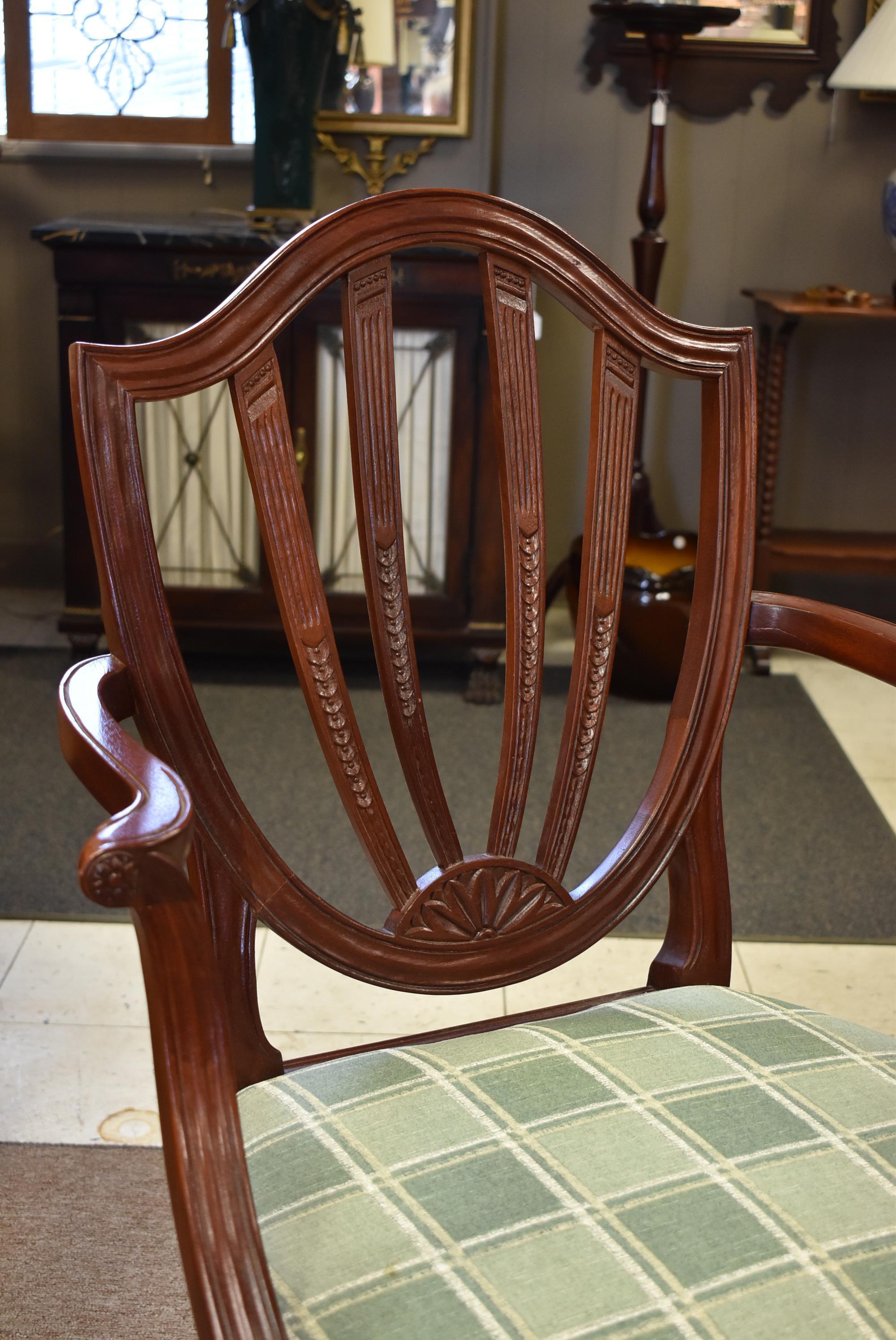 Six carved mahogany Sheraton style shield back chairs by Baker Furniture. Two arm chairs and four side chairs. Tapered fluted legs.