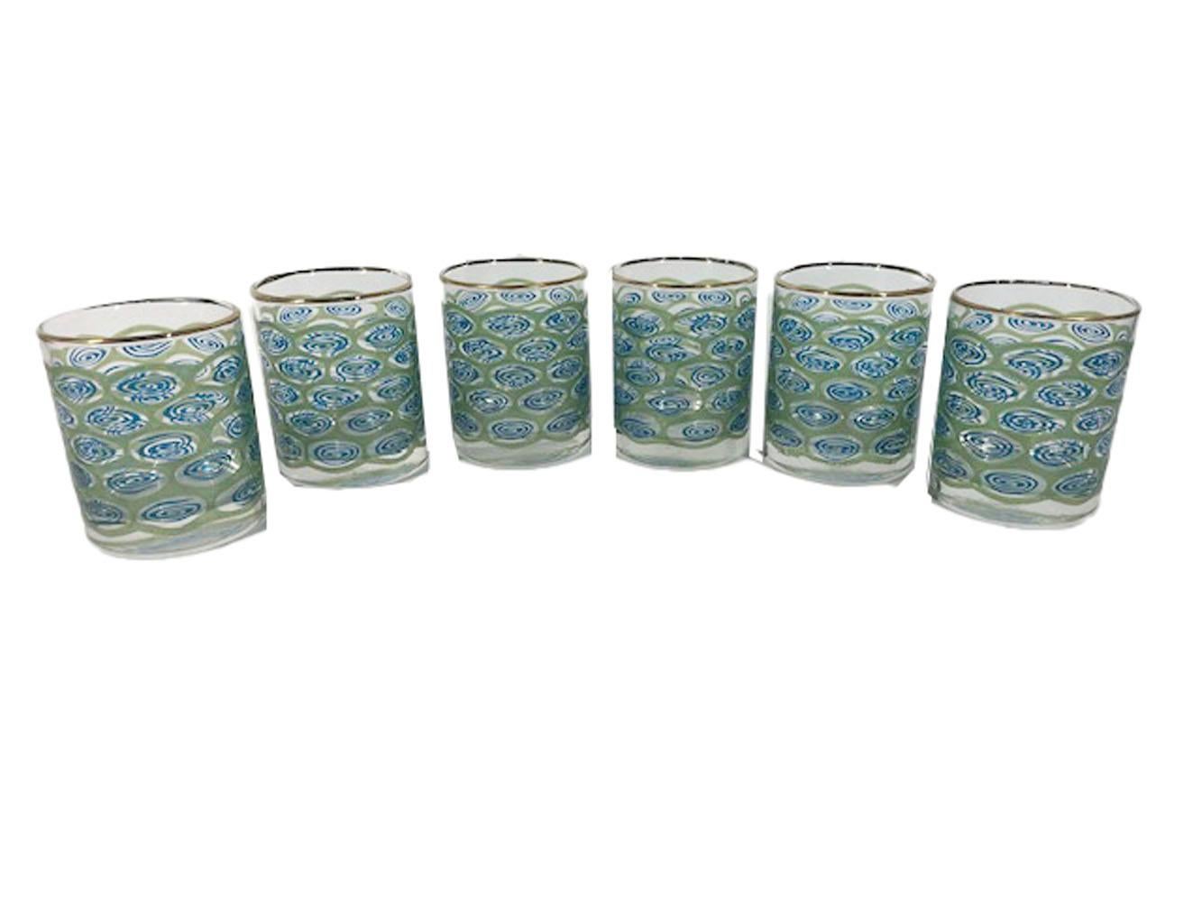 Six Libbey glass rocks glasses with gilded rims and of cylindrical form with raised translucent blue enamel swirls in a ground of raised translucent green enamel creating an abstracted design based on the 