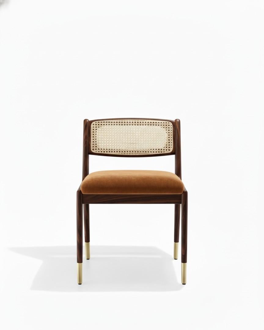 A Mid-Century Modern style dining chairs in ebony finished frame.
Ebony finished wood frame.
Backrest in natural woven cane.
Seat in cognac tan faux leather. 
Polished brass caps.

Dimensions: W 47 cm x D 61 cm x H 77 cm
Materials: Wood, faux