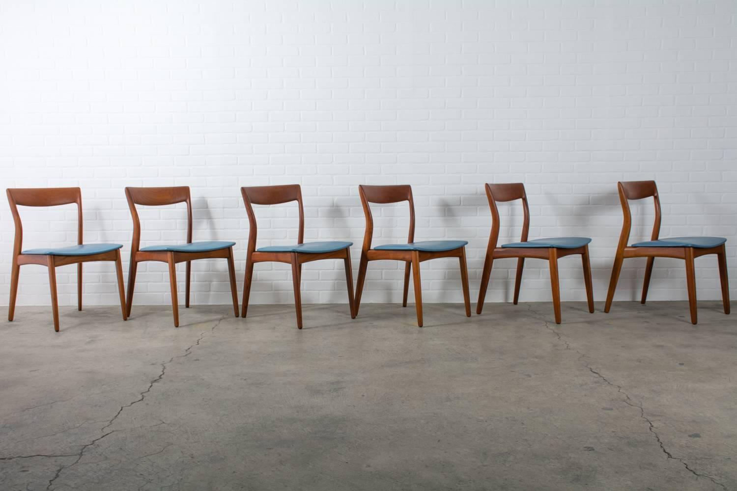 This is a set of six Danish Modern teak dining chairs designed by R. Borrogaard for Viborg Stolefabrik, Denmark. Beautiful curved back rests and original blue faux leather seats. Teak dining table available separately.