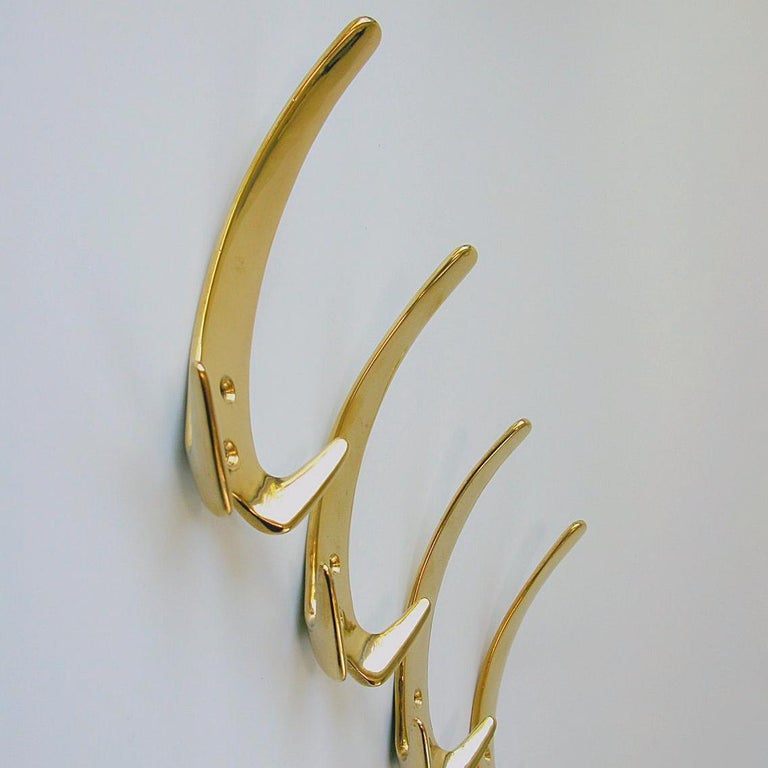 Six beautiful Austrian Mid-Century Modern solid brass hooks by Carl Auböck II. They are made of polished solid brass and come with the original brass screws. 
The same hooks were sold at an auction on 13 October 2016 in Chicago for 3.750 $ set of