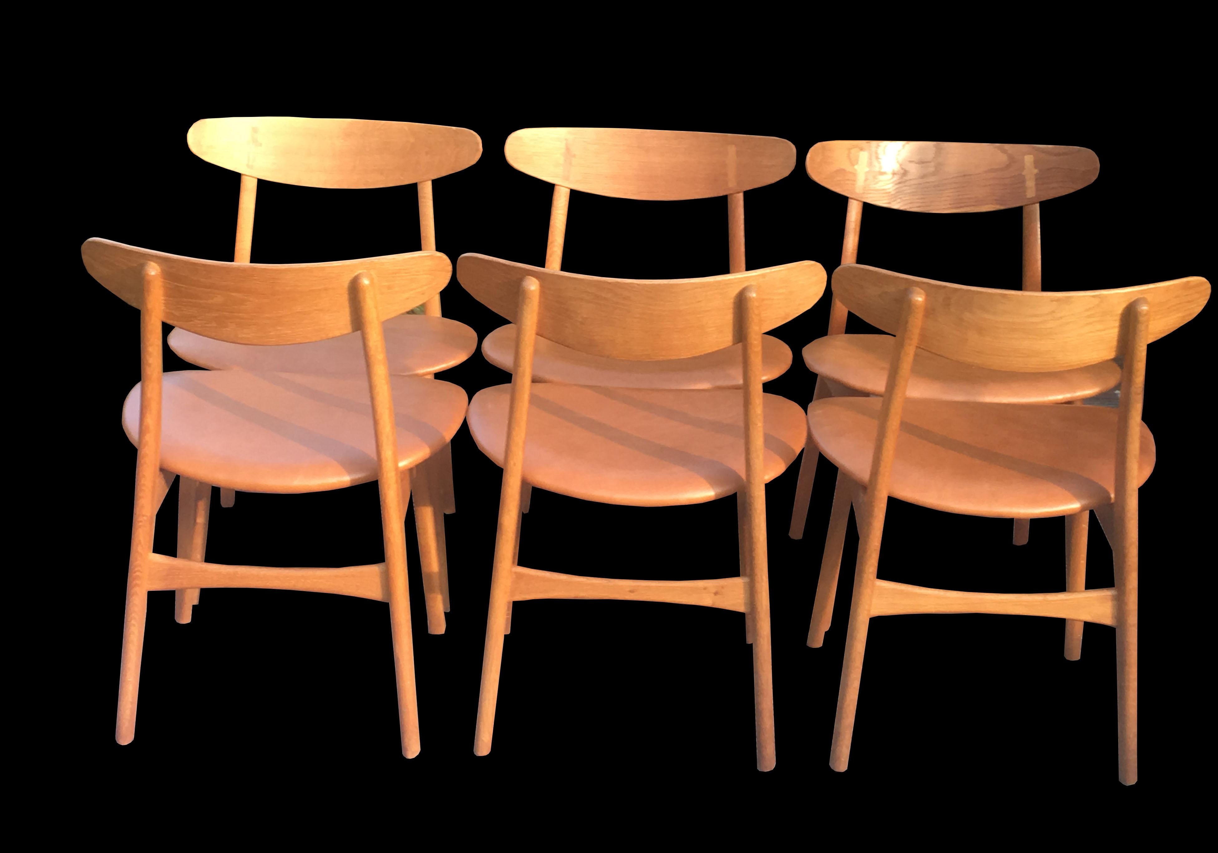A fine set of six CH30 oak dining chairs with cognac leather seat pads, by Hans J. Wegner, and produced by Carl Hansen & Son, all in very good condition.