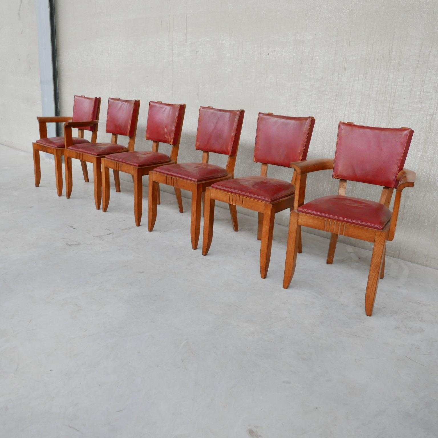 A set of six oak dining chairs. 

France, c1940s. 

Attributed to Charles Dudouyt. 

Original red leather heavily worn which needs updating, priced accordingly. It is best to have it upholstered in a fabric of one's choosing. 

Some age