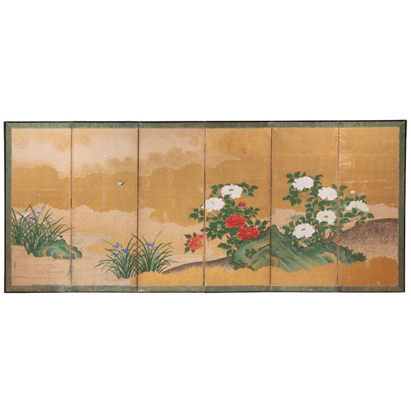 A six panel Japanese screen depicting a landscape scene peonies and sparrows against a gold backdrop of clouds and sky. The colors are vibrant with red and white peonies, green grasses and black, gray and white sparrows.  The screen is made of ink