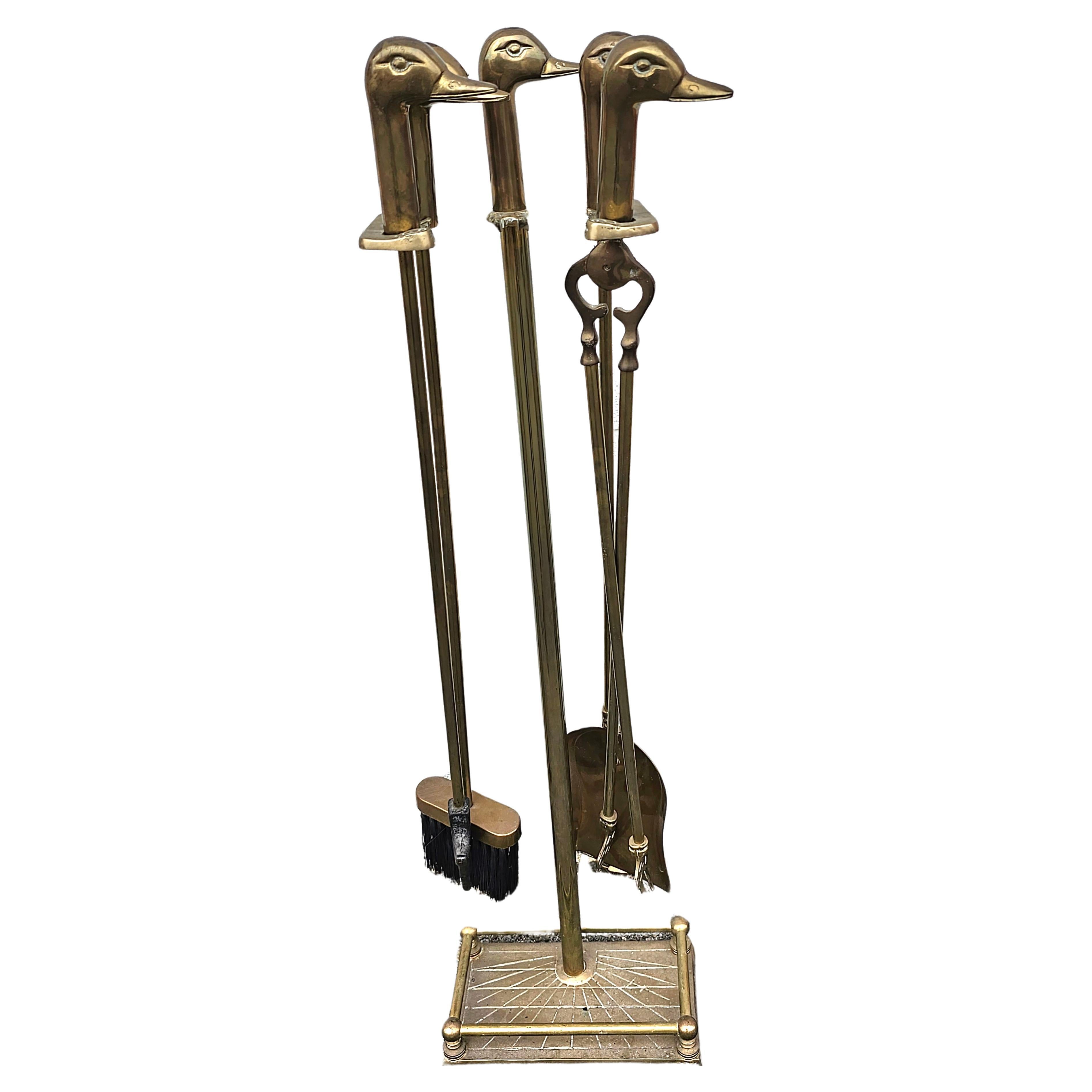 This is a vintage duck head themed fireplace 6 piece  tool set. Figurative duck heads shape the handles of the classic brass fireplace tools and stand. The base has an art deco design. The set includes the stand, a poker, tongs, shovel, and brush.