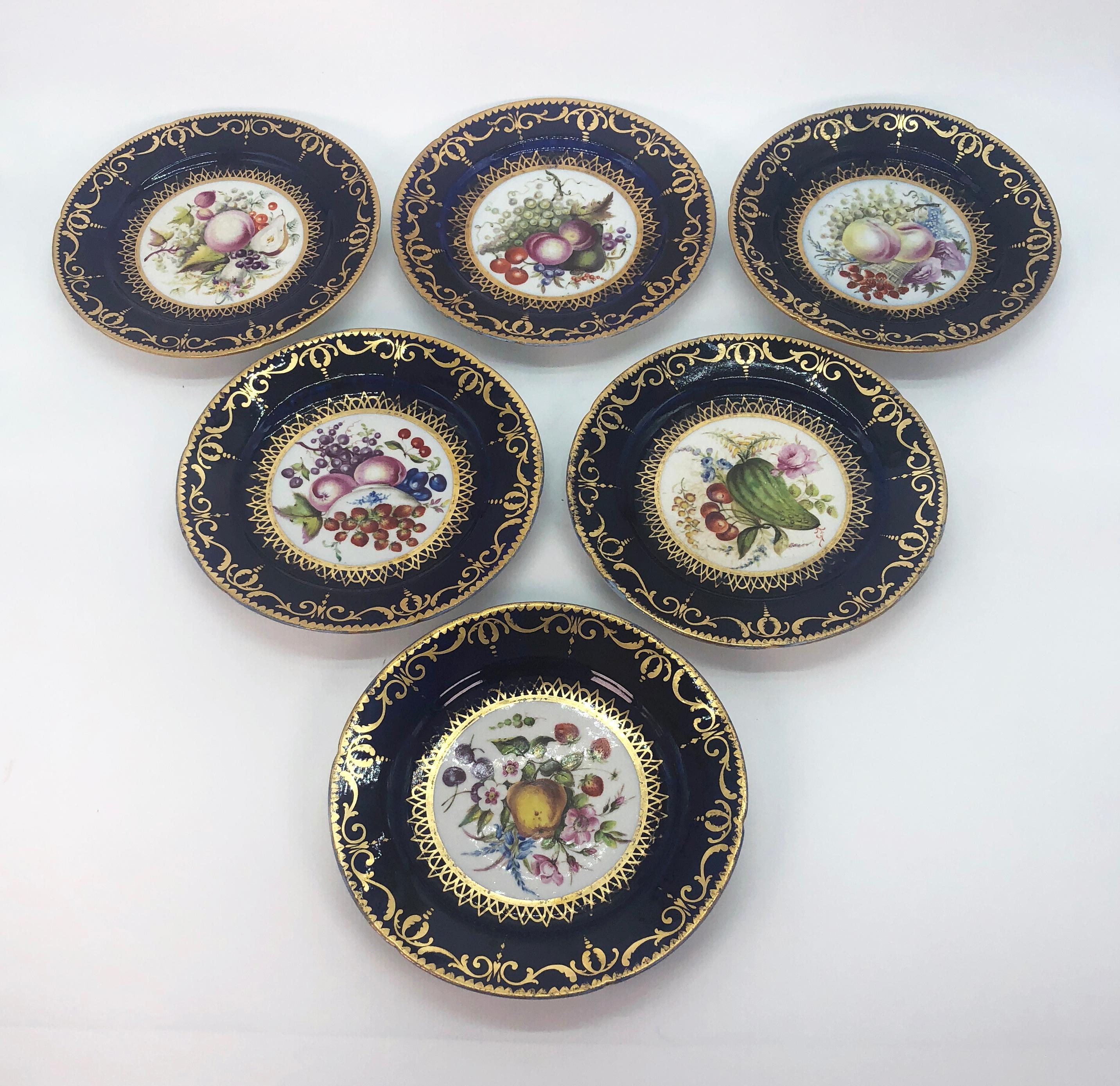 Six Regency side plates by Coalport with hand painted panels of fruit, circa 1805. Cobalt borders support a gilded band of interlocking scrolls and finials with a gold dentil border. Hand painted panels of fruit and flora in the manner of the