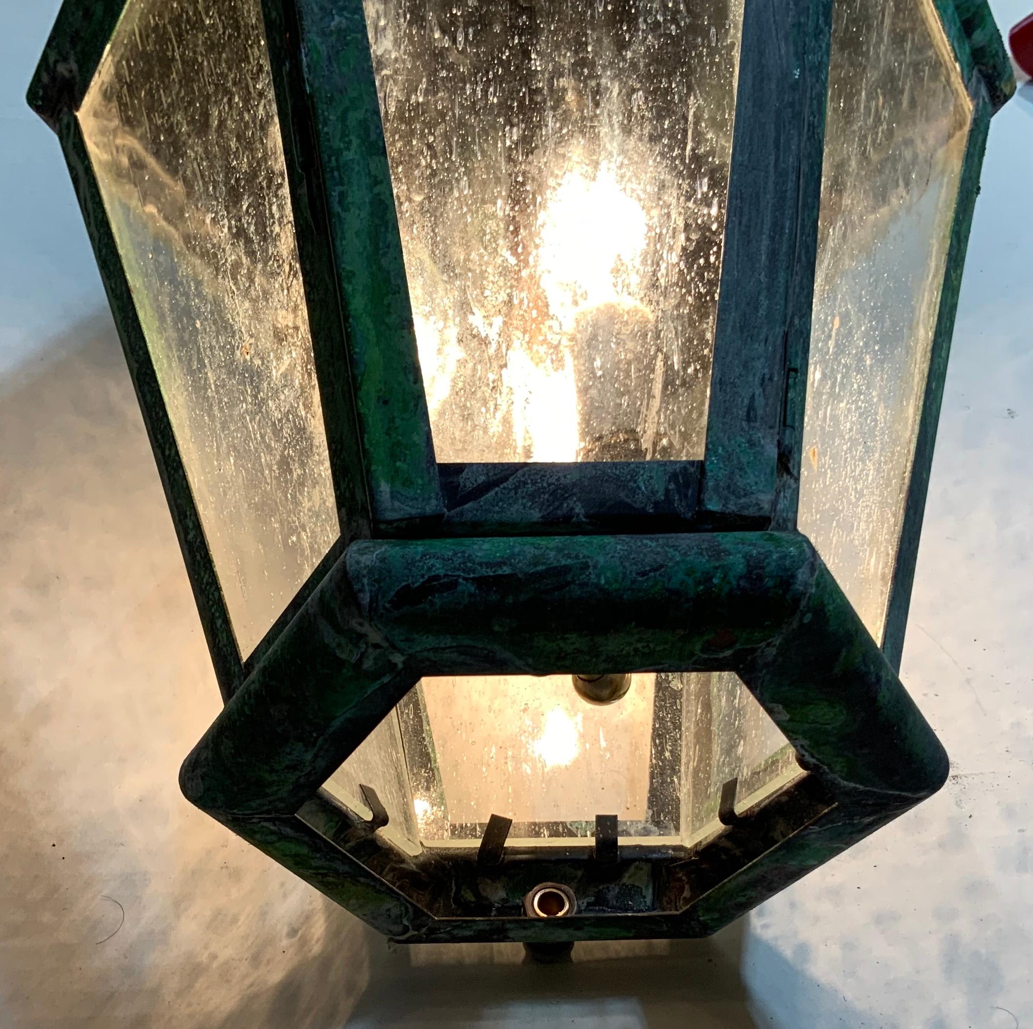 Beautiful patina, six sides hanging lantern made of solid brass, the top of the lantern is close with brass instead glass to direct the light to the sides and to the bottom. Seeded glass, newly electrified with three
60/watt brass cluster.