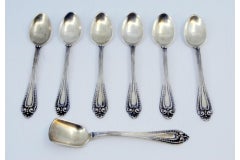 Six silver coffee spoons and sugar shovel with reliefs and grooved handles