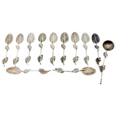 Six silver spoons and sugar shovel with raised handles and ribbed shell bowls