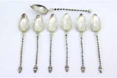 Six silver teaspoons and sugar scoop with twisted handles and acorn appliqués