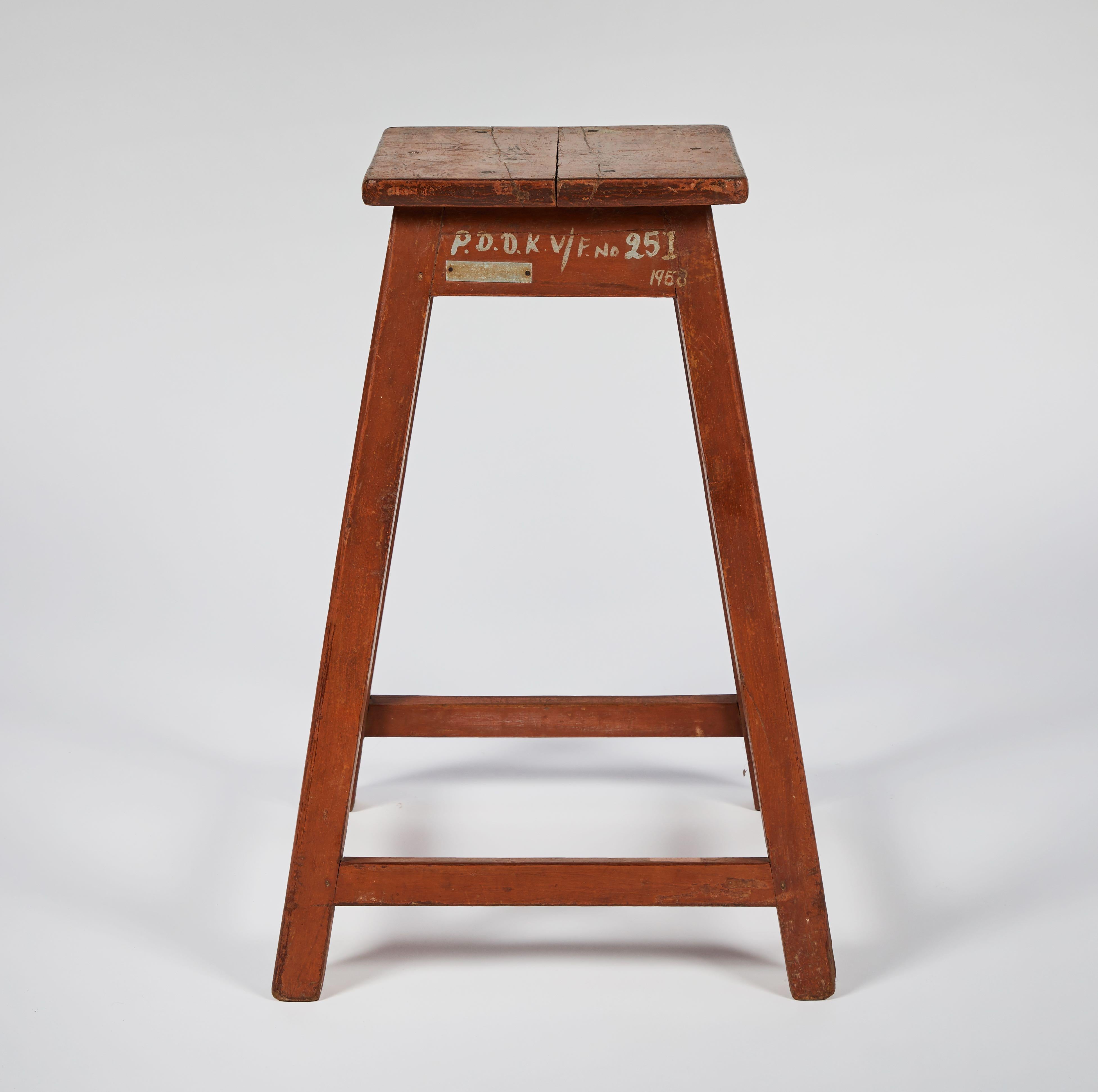 Six wooden factory stools from late 19th-century France. The cheerful red paint has taken on a fantastic patina from age and use. With square seats and block-shaped legs connected on all sides by a stretcher or footrest, these stools have straight,