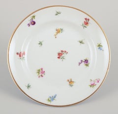Six small porcelain plates with polychrome floral motifs and gold rim.