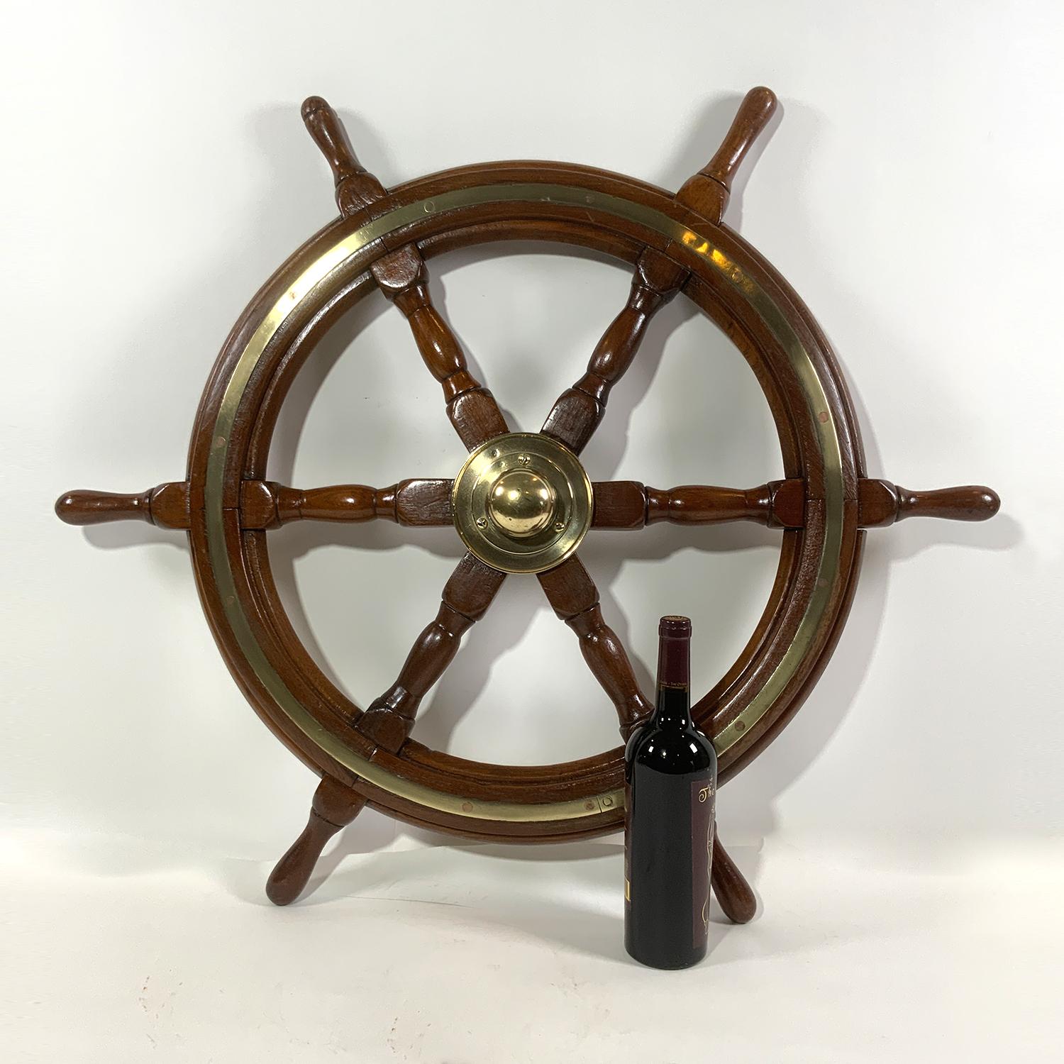 Varnish wood ships wheel with substantial brass hub and brass trim ring around hub and brass trim around the circumference. Varnish finish on wood.