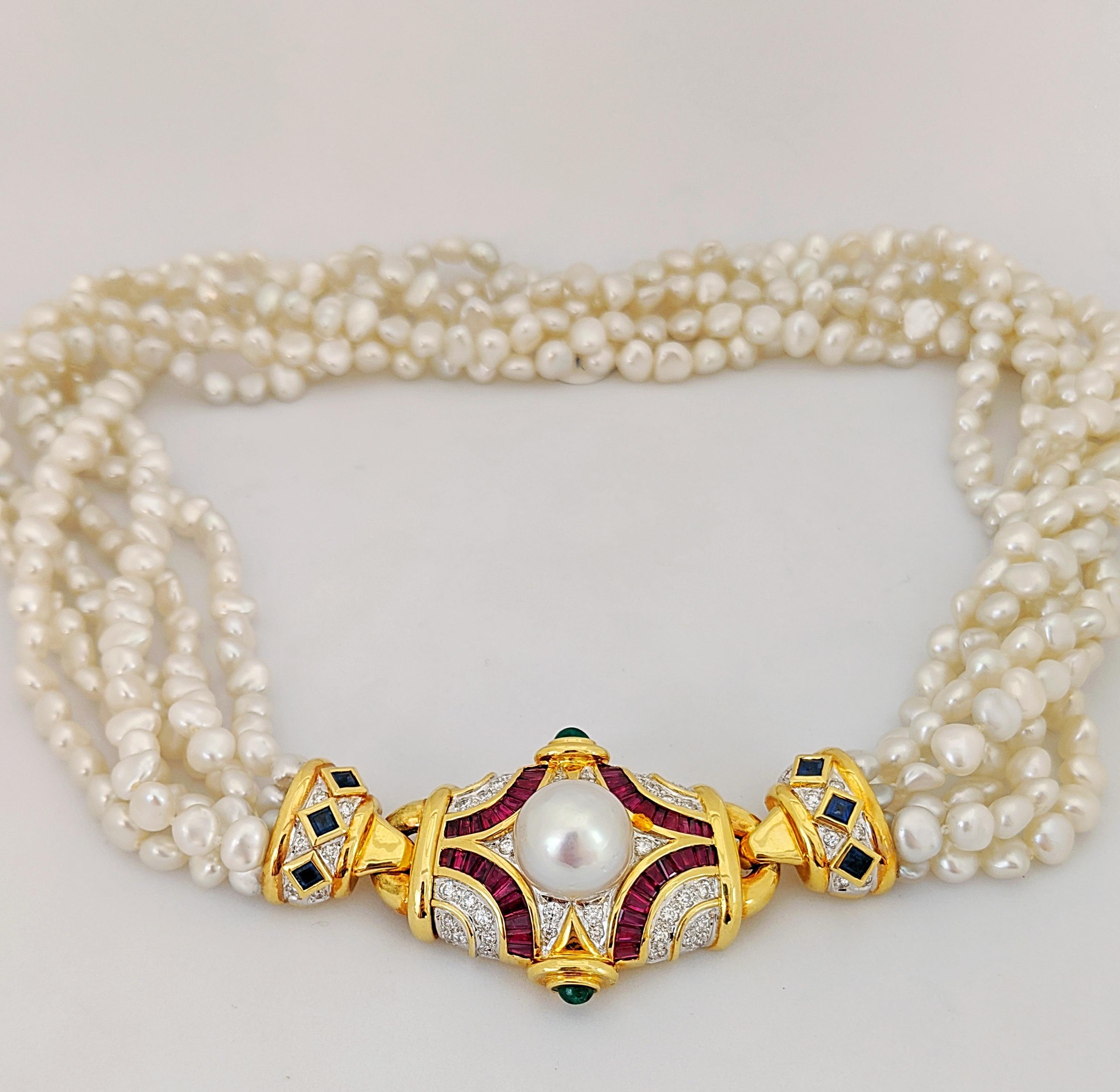 This exquisite necklace feature 18 karat yellow gold clasp set with round brilliant cut Diamonds and baguette cut Rubies. The piece is further accented with cabachon Emeralds and a 12.5 mm South Sea Pearl. The two end pieces are set with Diamonds